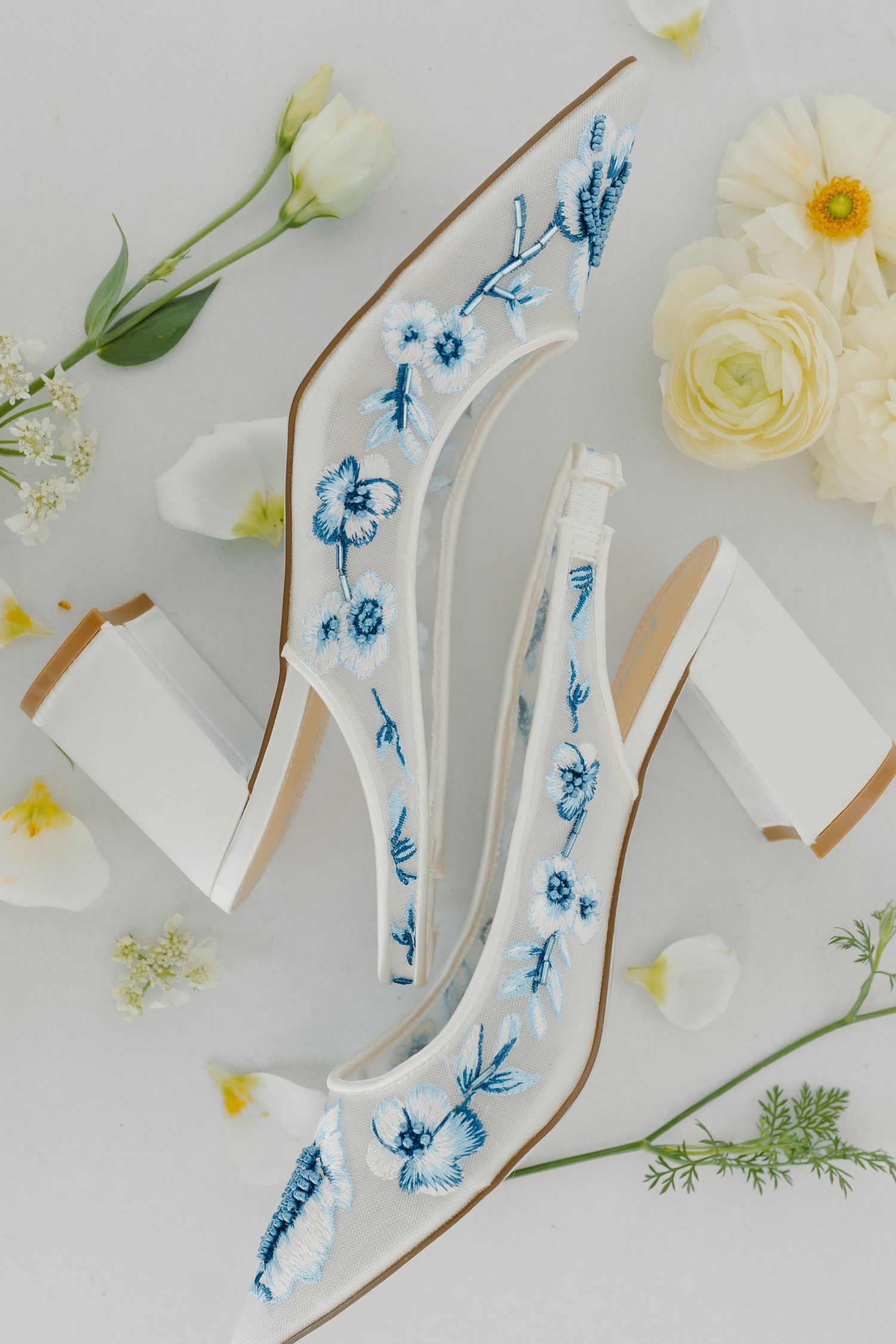 White ceramic art piece with blue floral designs surrounded by fresh white flowers.