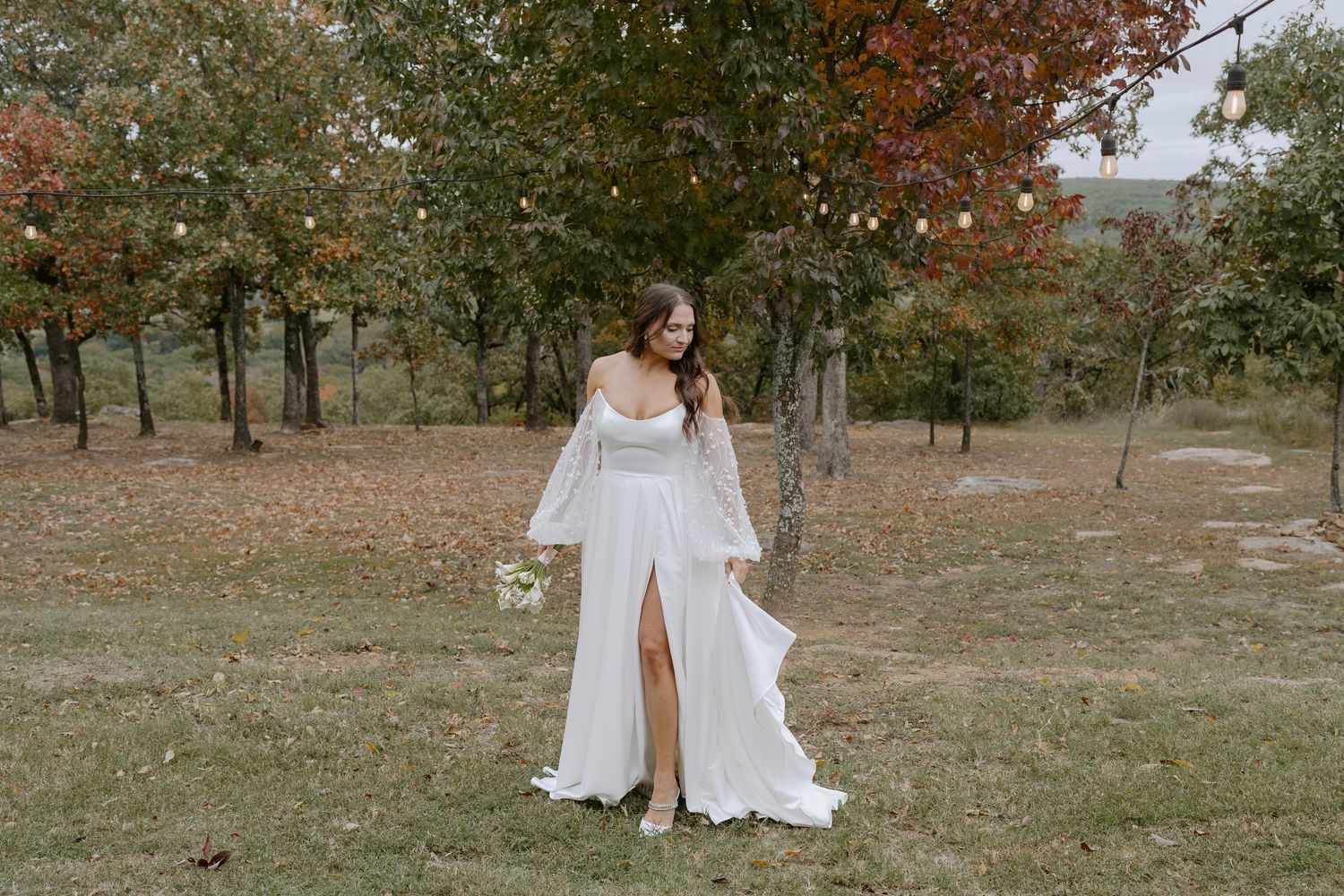 White wedding dresses billow in the breeze during an outdoor autumn photoshoot.