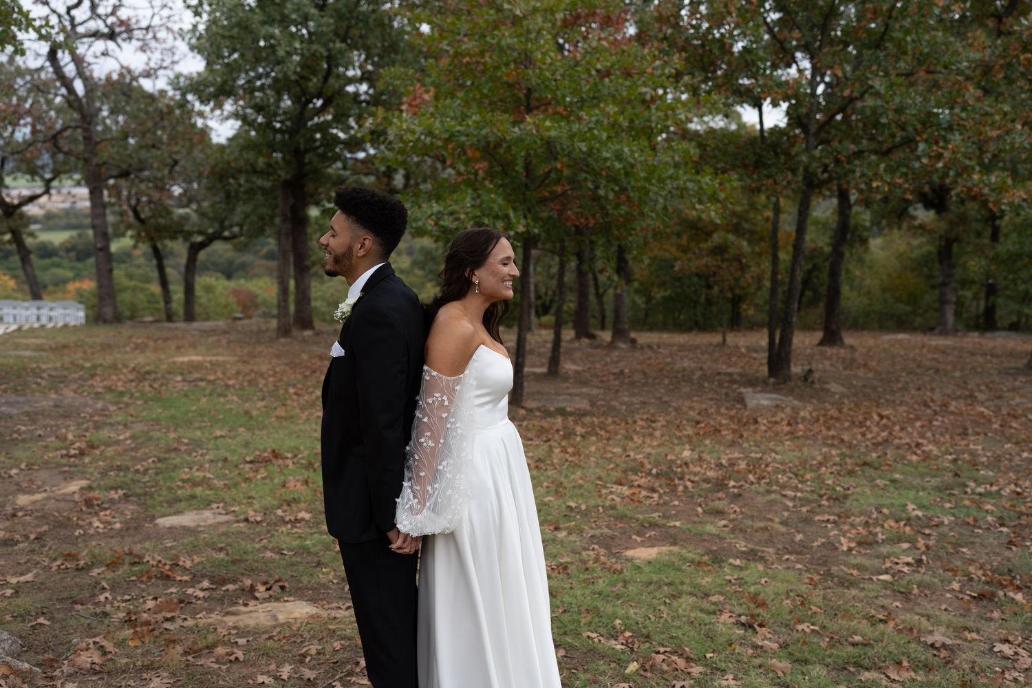 A wedding couple poses together in a scenic fall landscape.