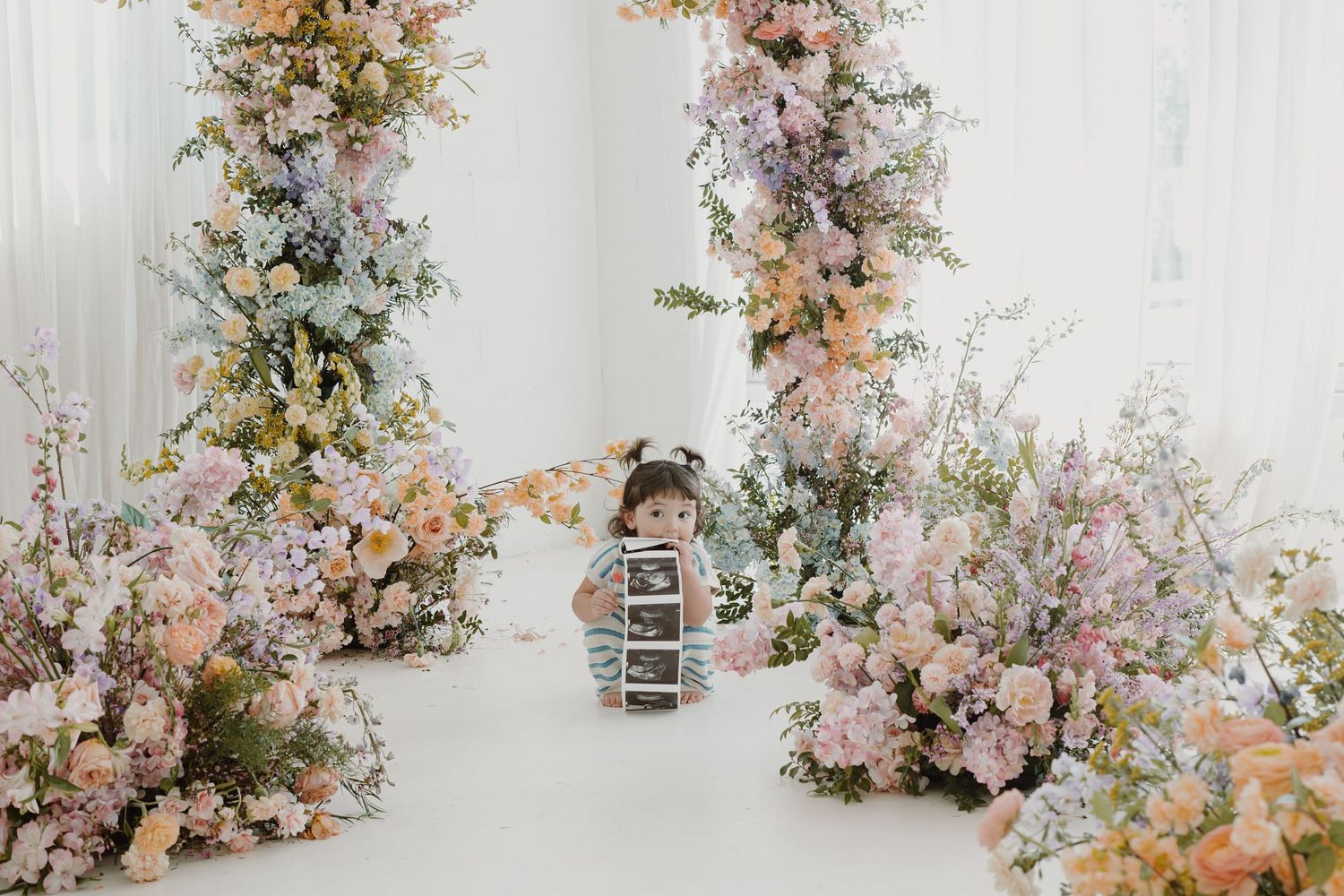Elegant floral installation with pink and peach blooms against white studio backdrop.