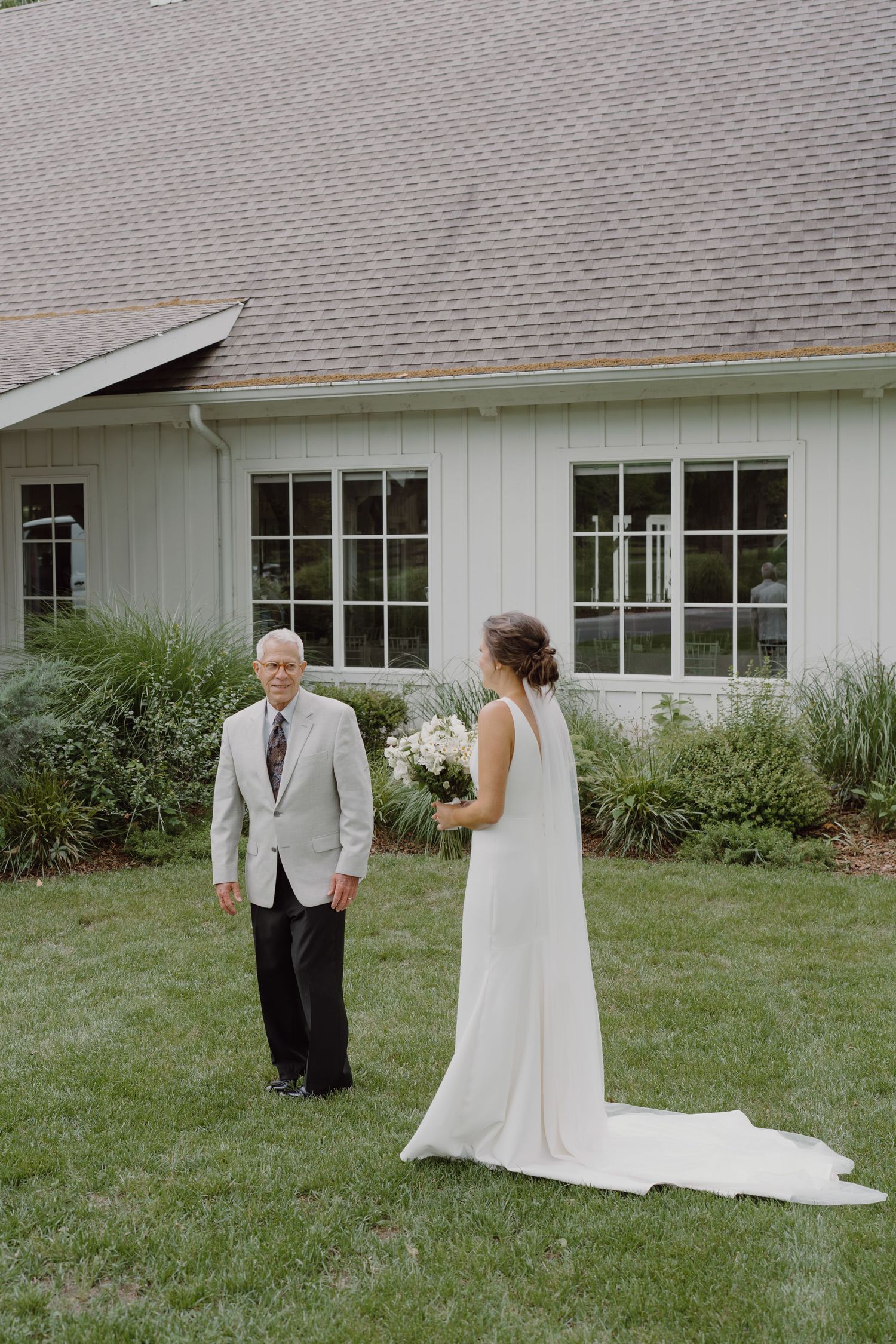 A series of wedding photos showing a first look moment in front of a white building.