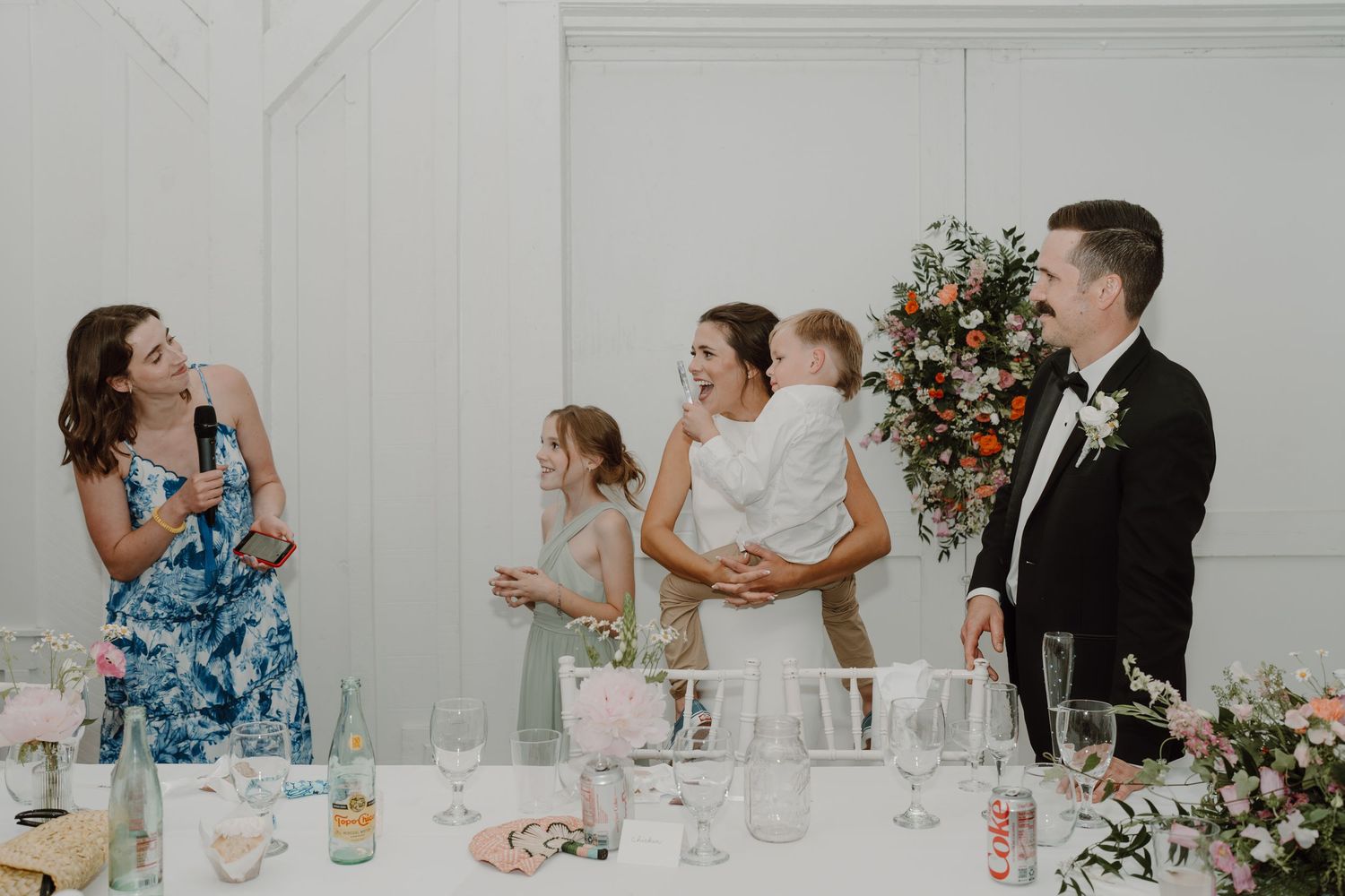 Wedding reception guests mingle and celebrate in an elegant white venue.