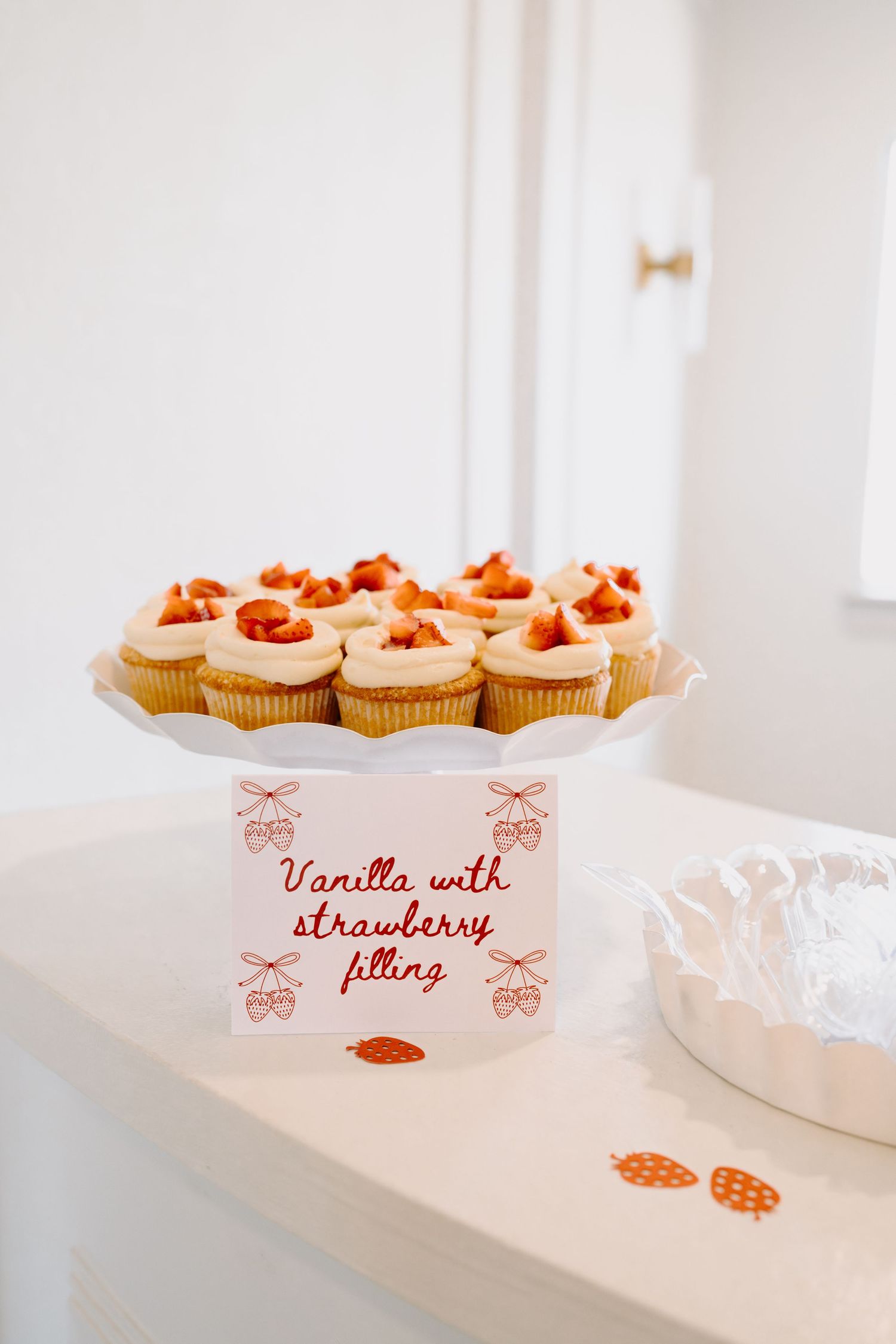 Display of cupcakes with pink labels indicating vanilla and strawberry filling varieties.