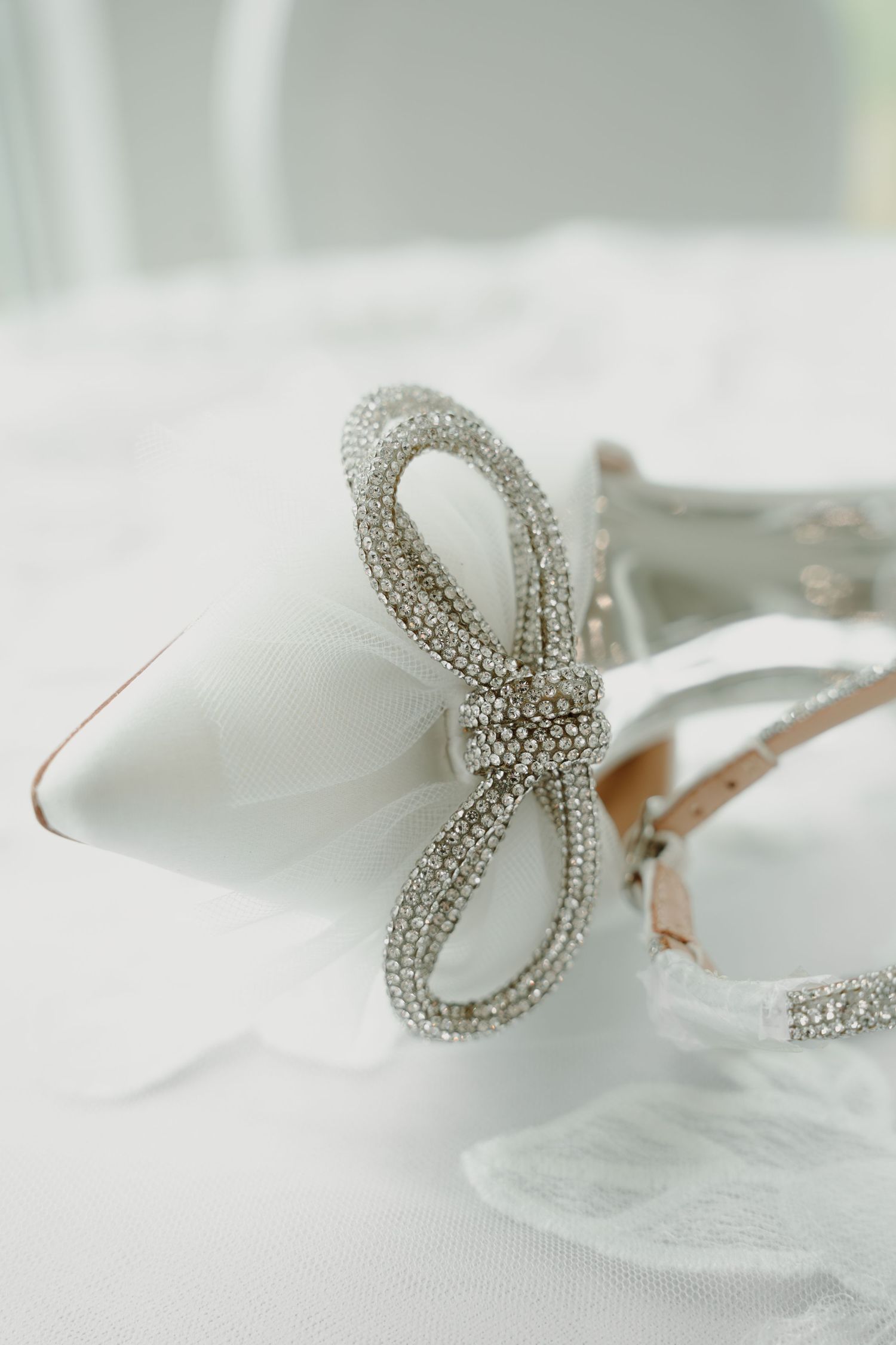 Crystal-embellished bow hair accessory photographed on white fabric.