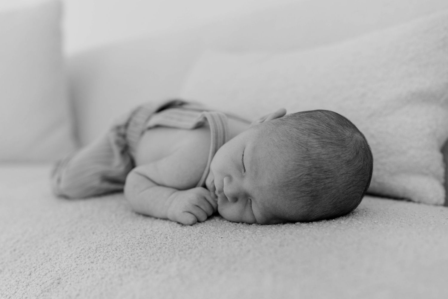 Close-up of a sleeping newborn baby's feet and toes on white bedding.
