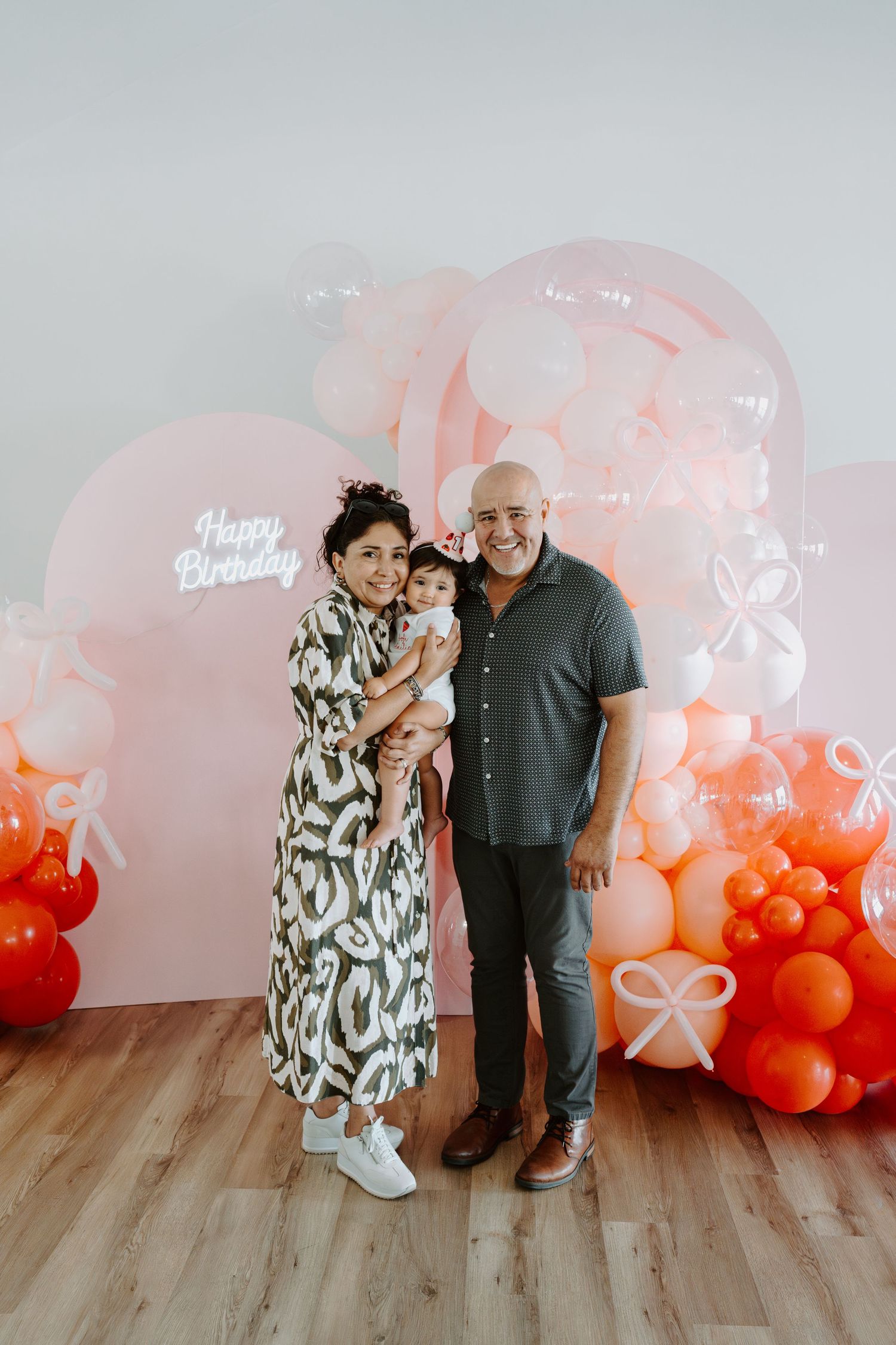 Casual family photo shoot with festive balloon decorations in the background.