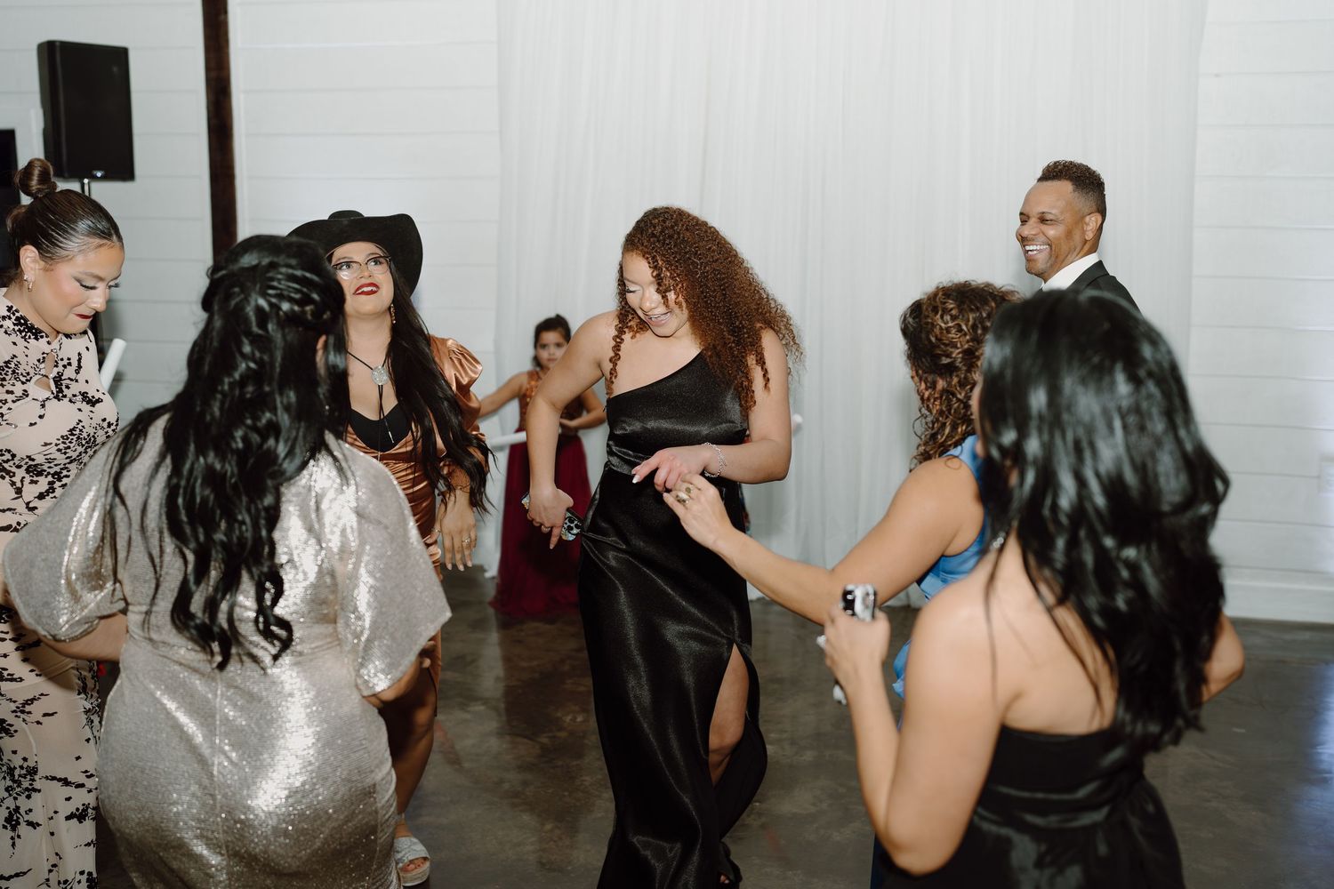 Wedding party members dancing together during evening reception celebrations.