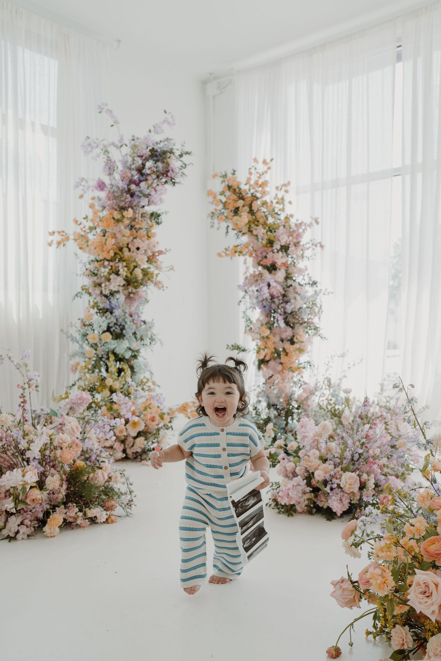 Bright studio setup with striped outfit and beautiful floral installations.