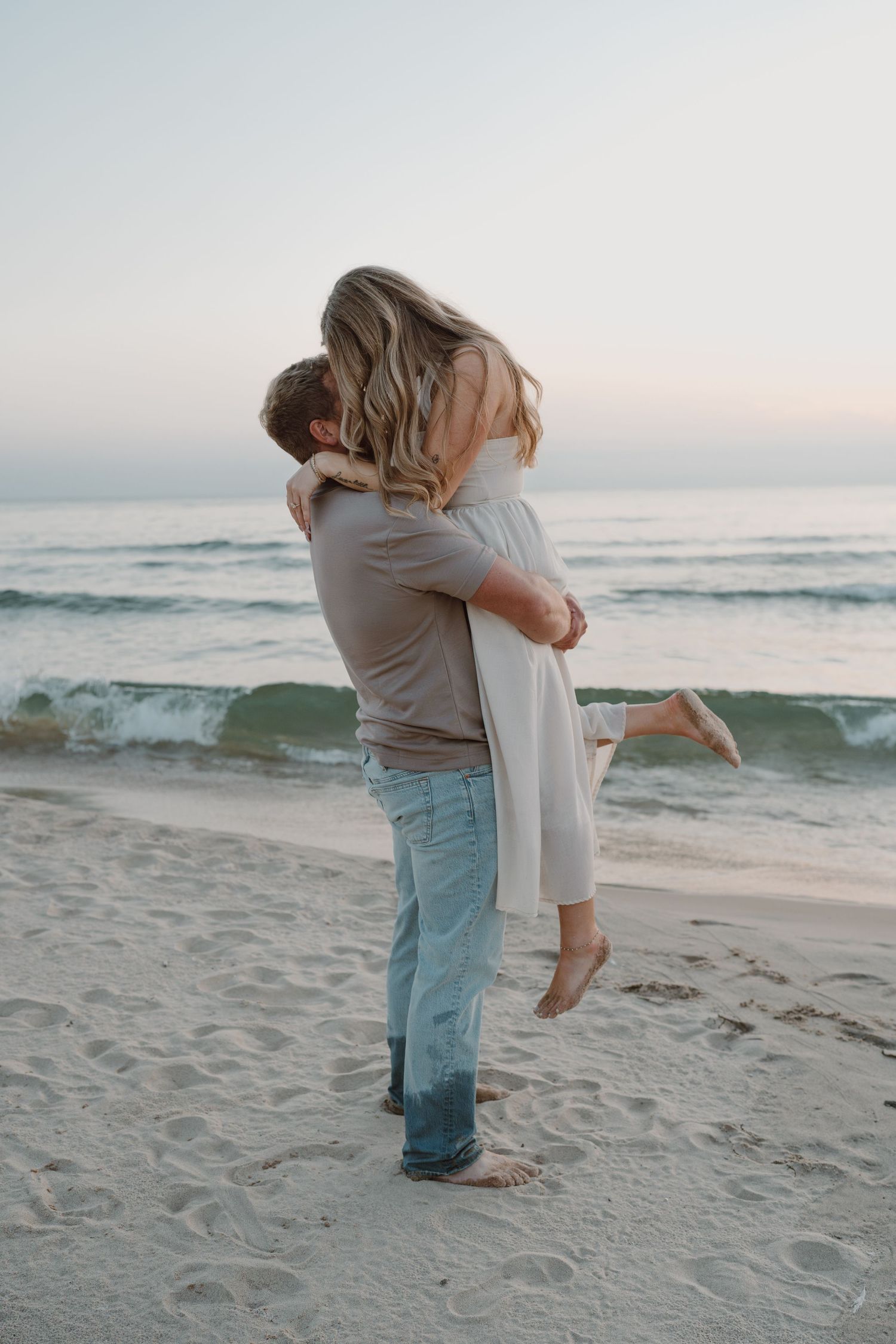 A couple shares a tender embrace on a peaceful beach during sunset.