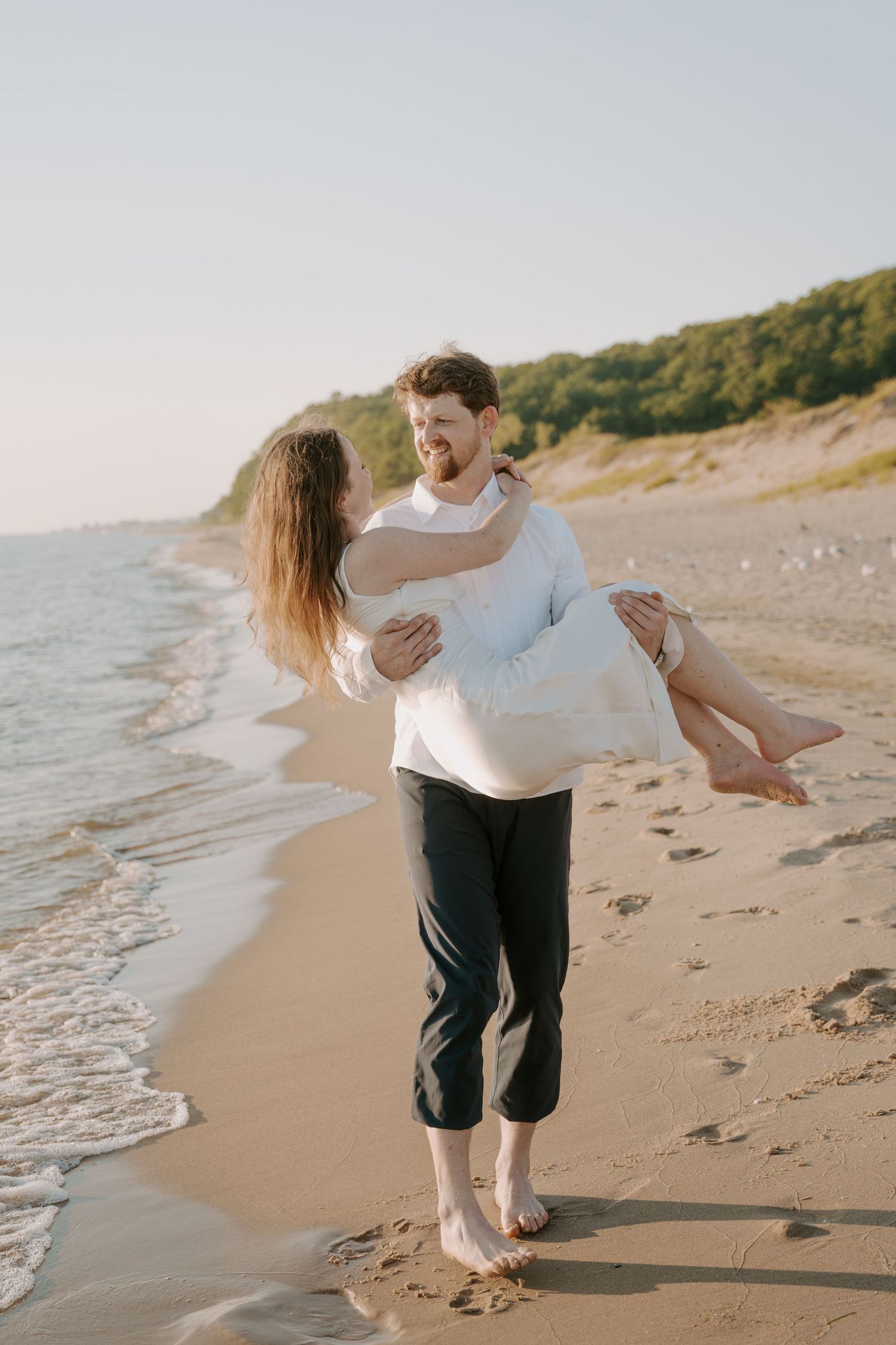 Romantic moment captured on a sandy beach with gentle waves in the background.
