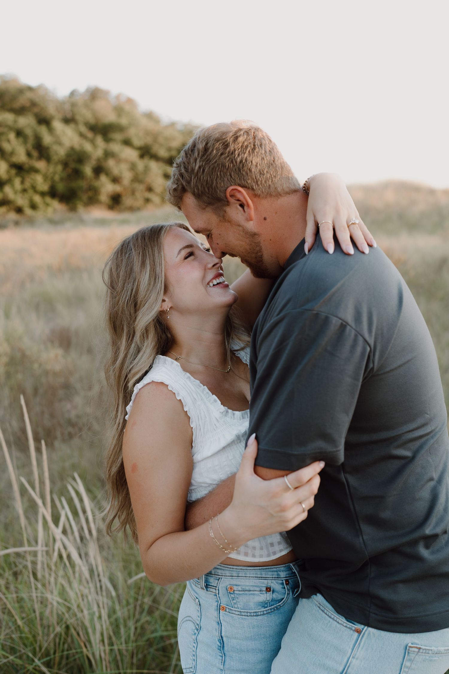 Romantic couple photography session on coastal dunes during sunset.