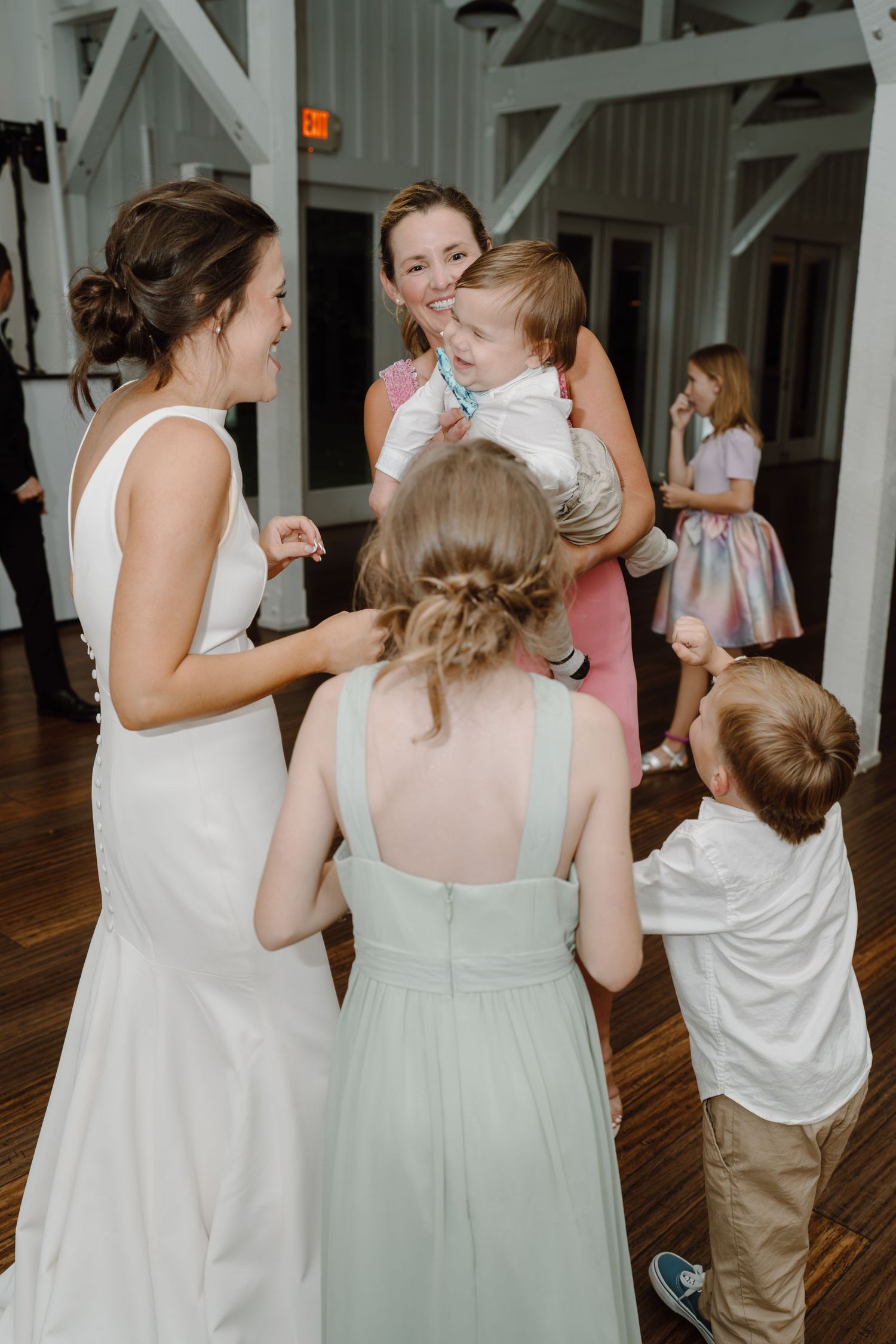 Wedding guests dancing together in casual attire at a reception venue.
