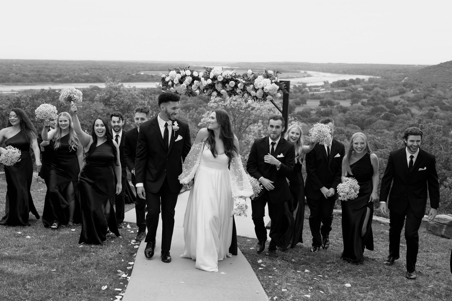Panoramic shot of wedding guests gathered on hillside during outdoor ceremony.