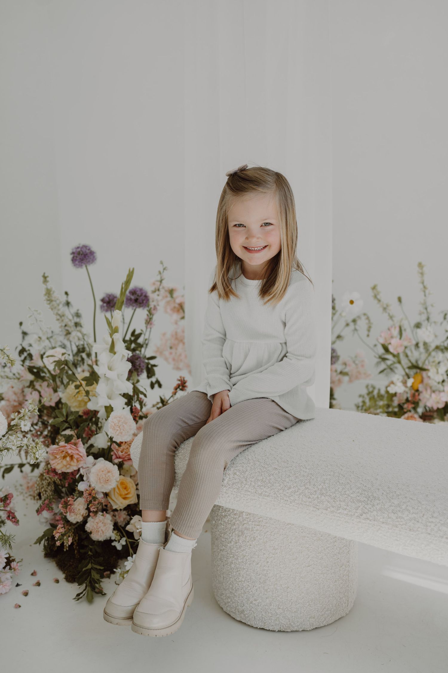 Natural light portrait with delicate floral arrangements and modern white furniture.