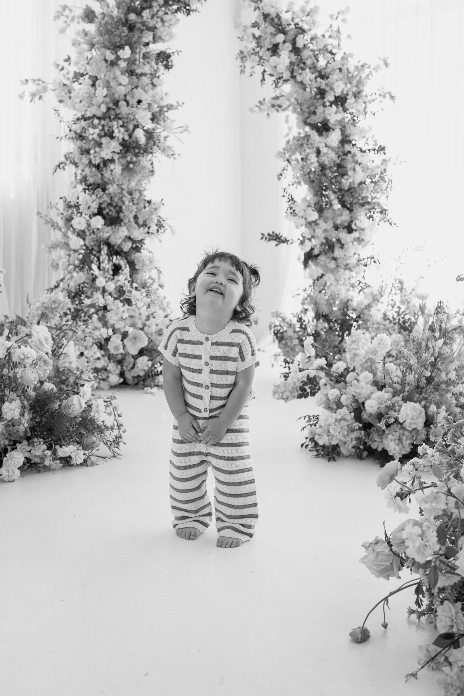 Black and white portrait session with floral arrangements in a bright studio setting.