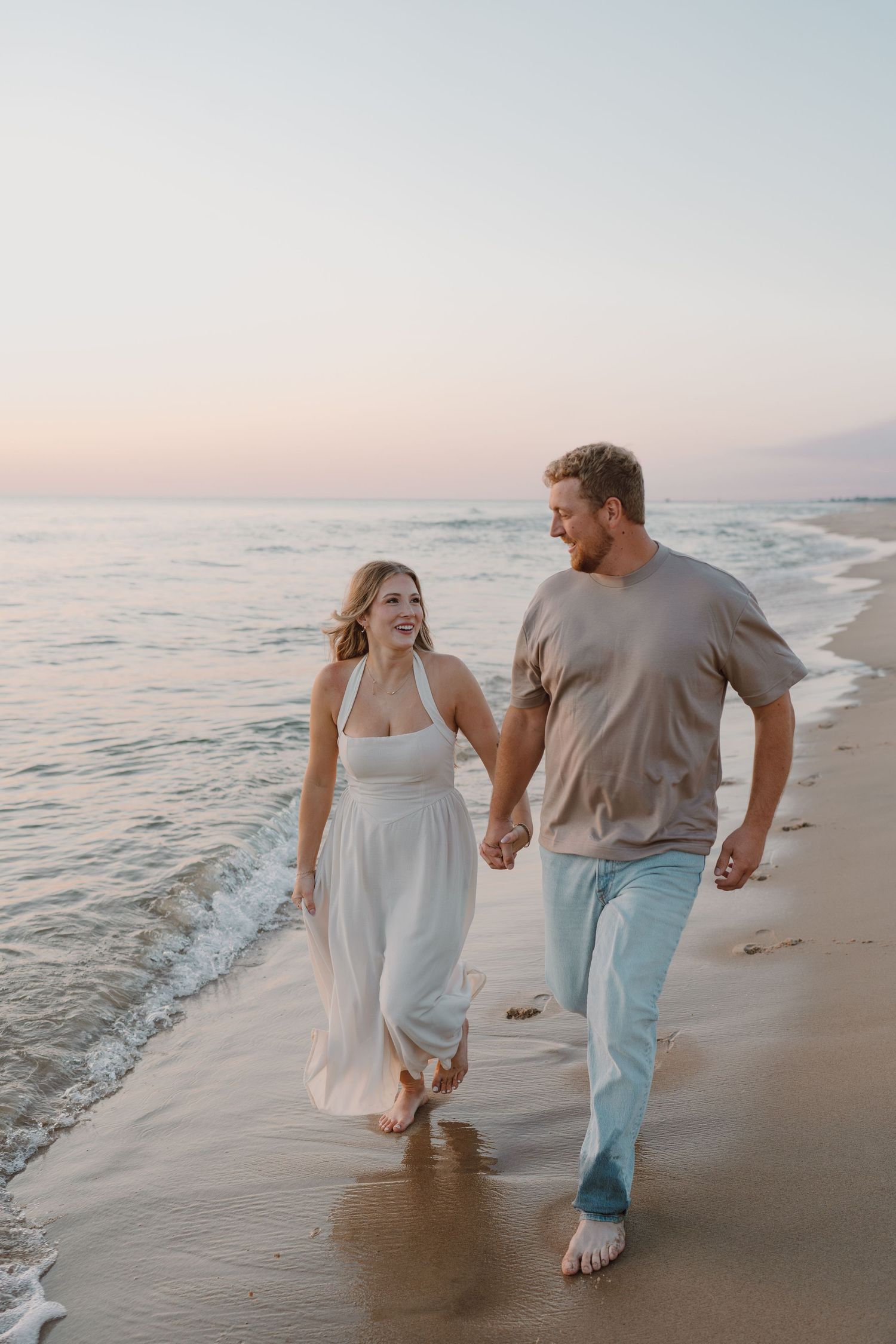 Couple in light summer clothing enjoying a carefree moment on sandy beach.