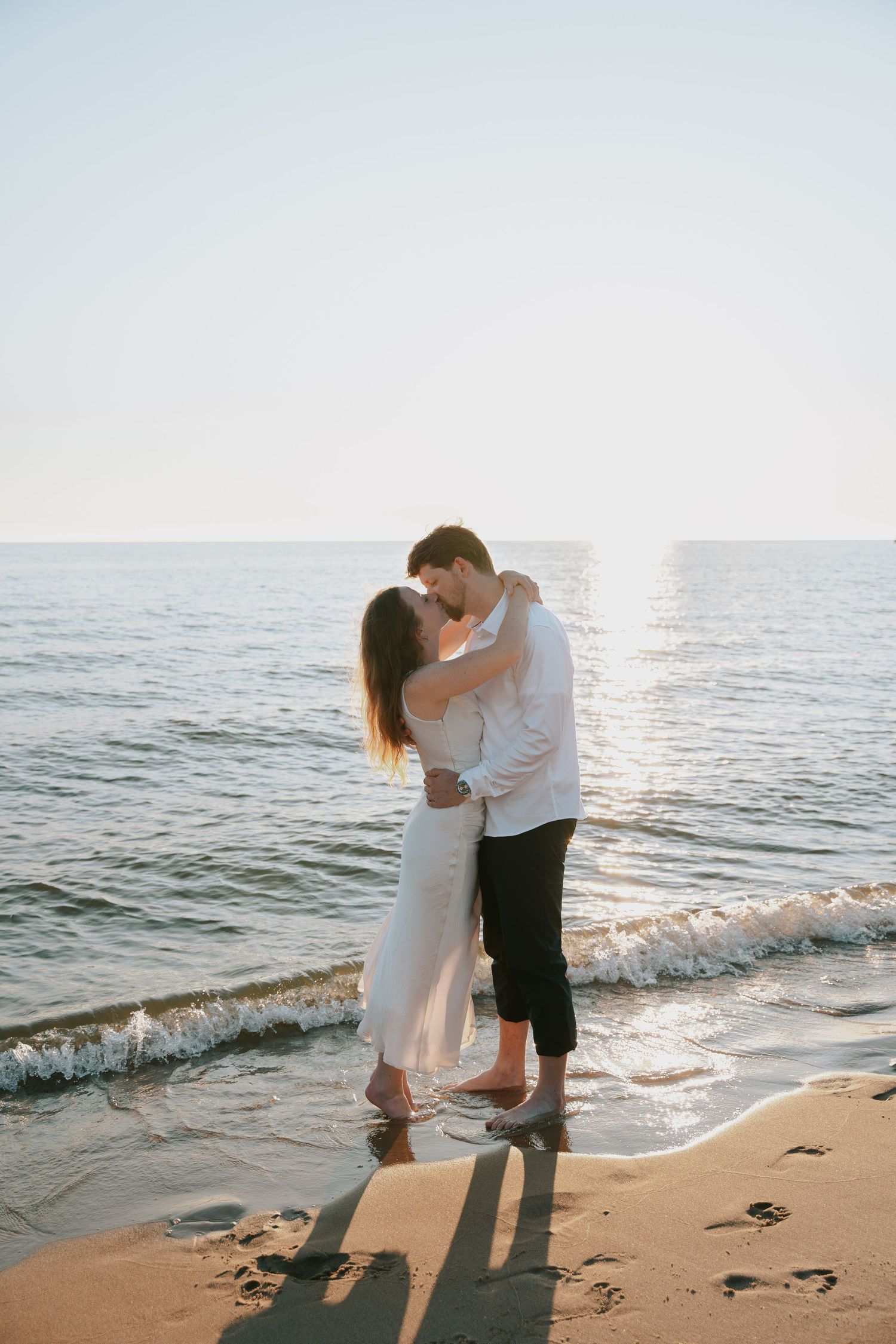 A tender moment between a couple on the beach at sunset.