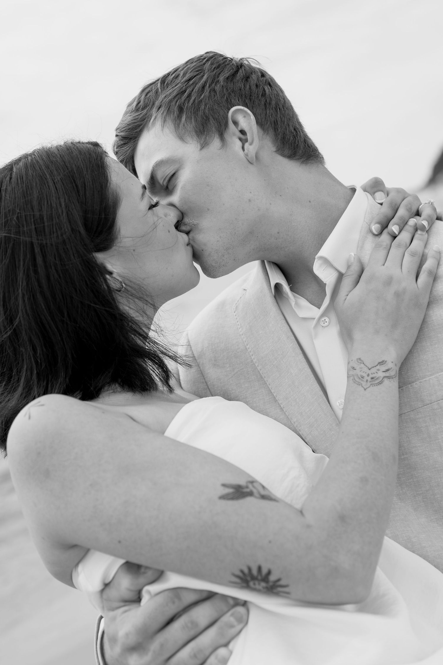 Intimate black and white close-up of couple sharing tender moment on beach.