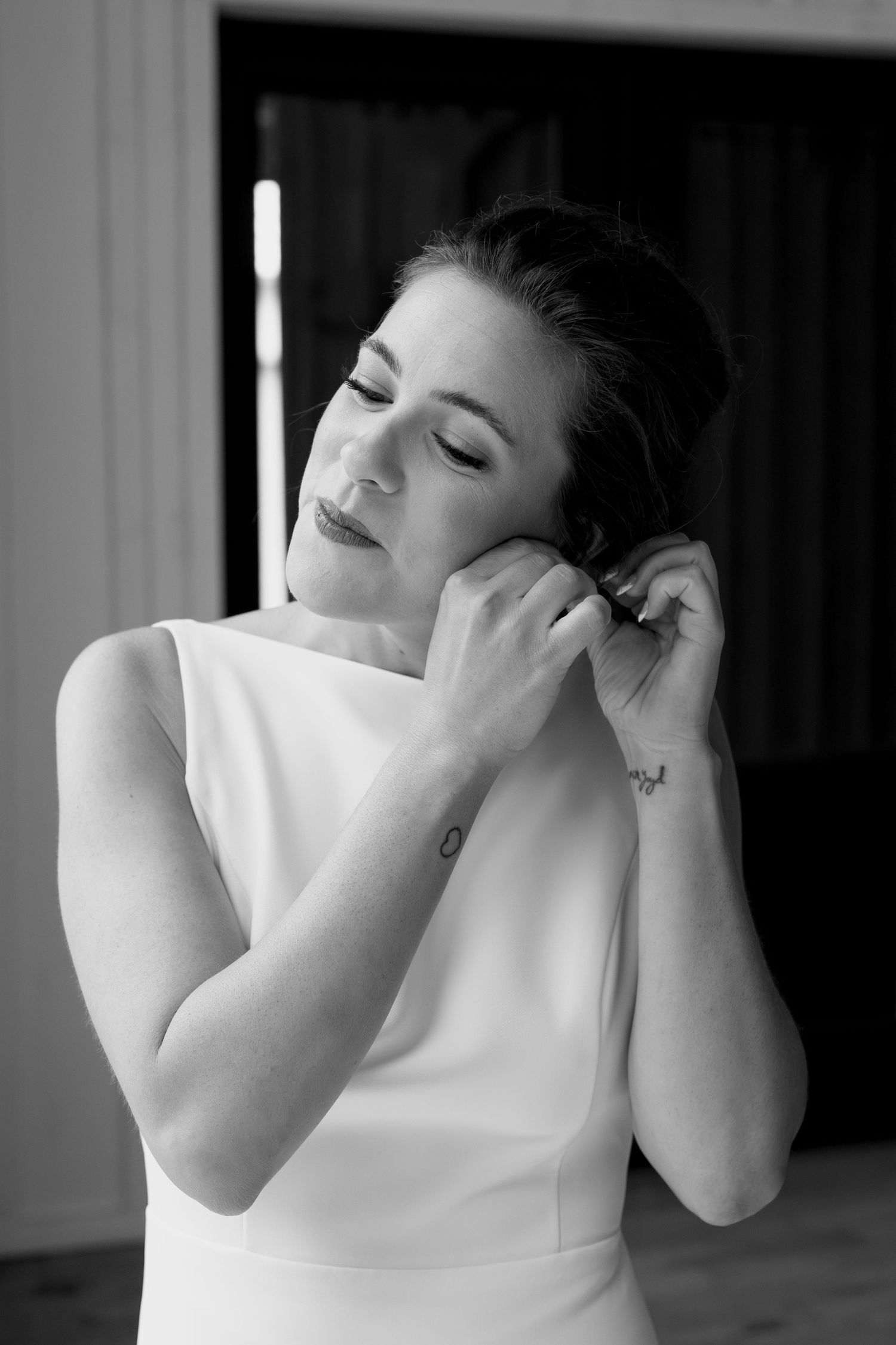 Artistic black and white portrait of a bride adjusting her earrings.