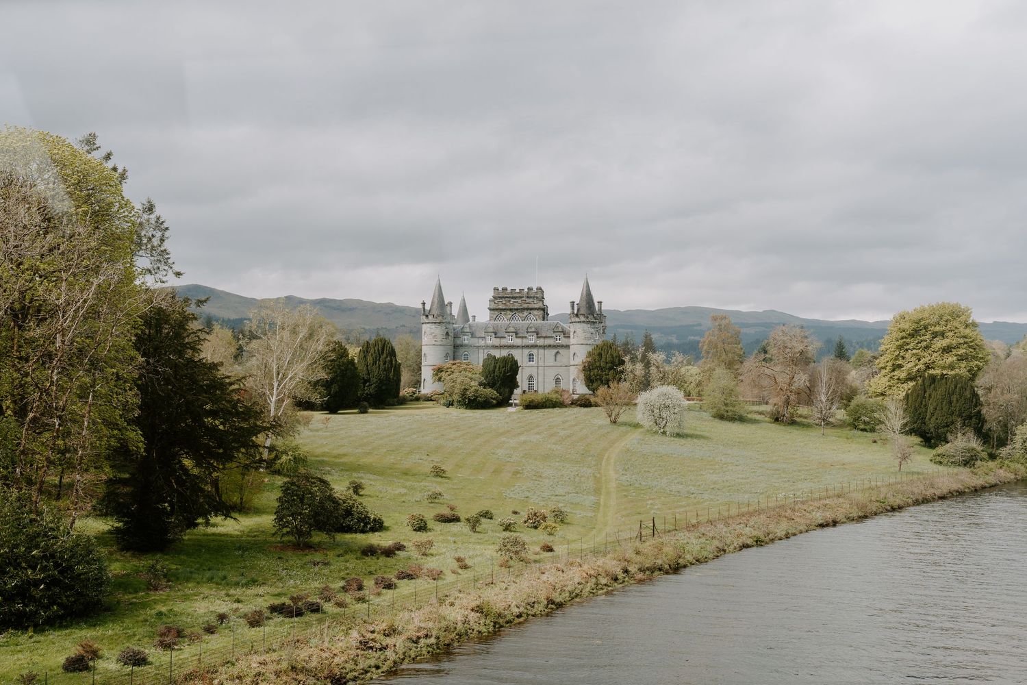 Panoramic view of a Scottish countryside with rolling hills and historic buildings in the distance.