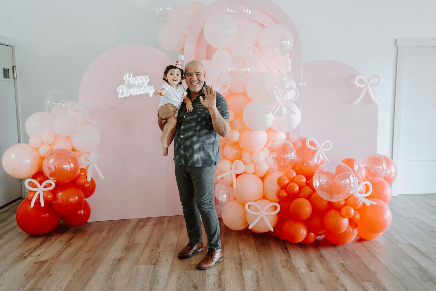 Elegant balloon installation featuring pink and coral tones with 'Happy Birthday' text on wall.