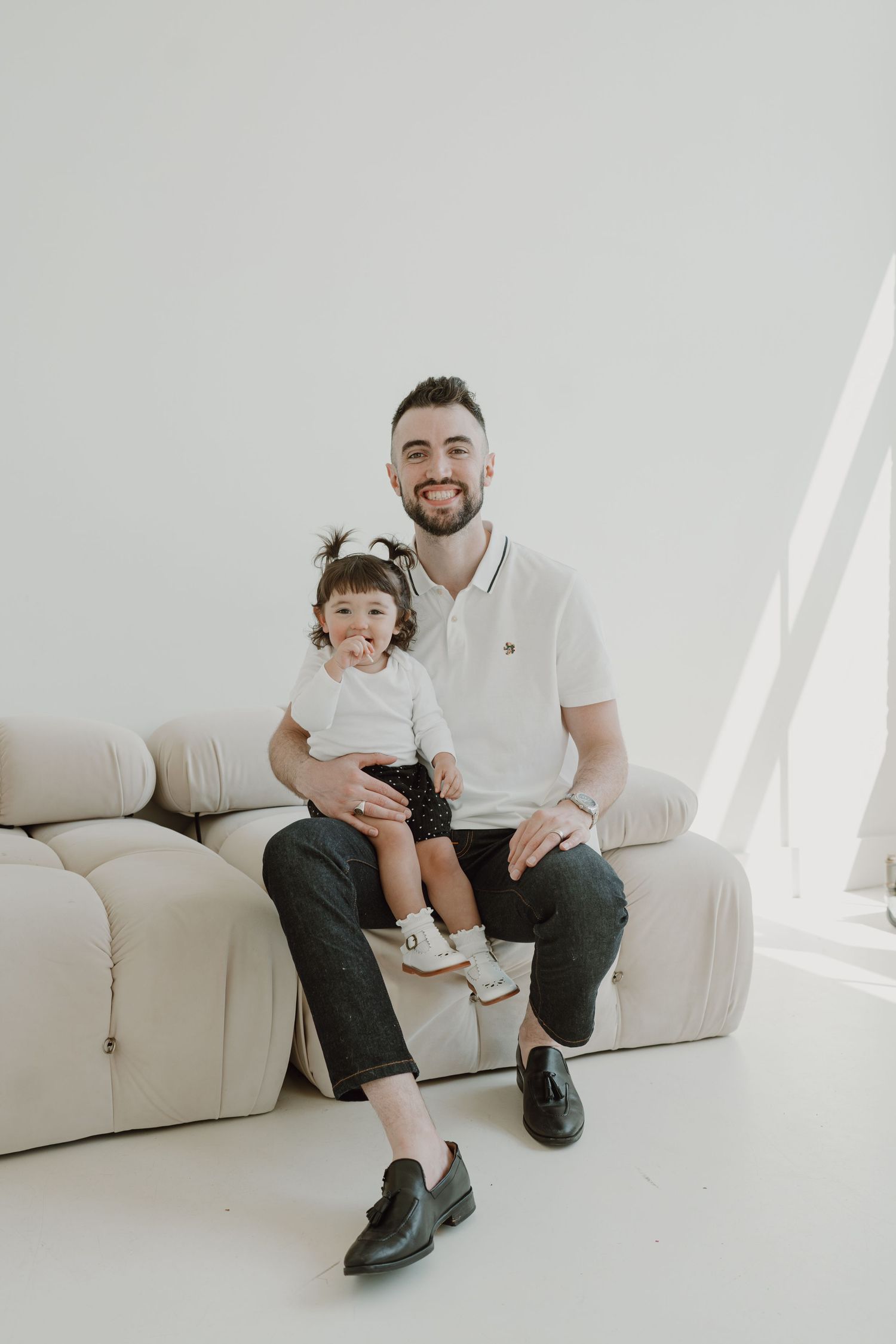 Sweet family photoshoot in a minimalist white studio with natural window light.