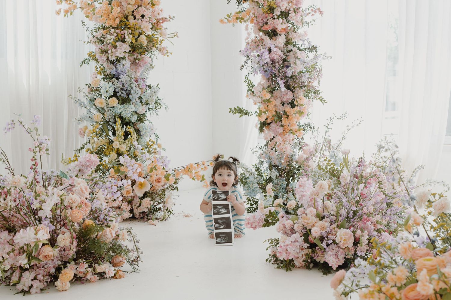 Dreamy studio setup with cascading floral arrangements in soft pastel colors.
