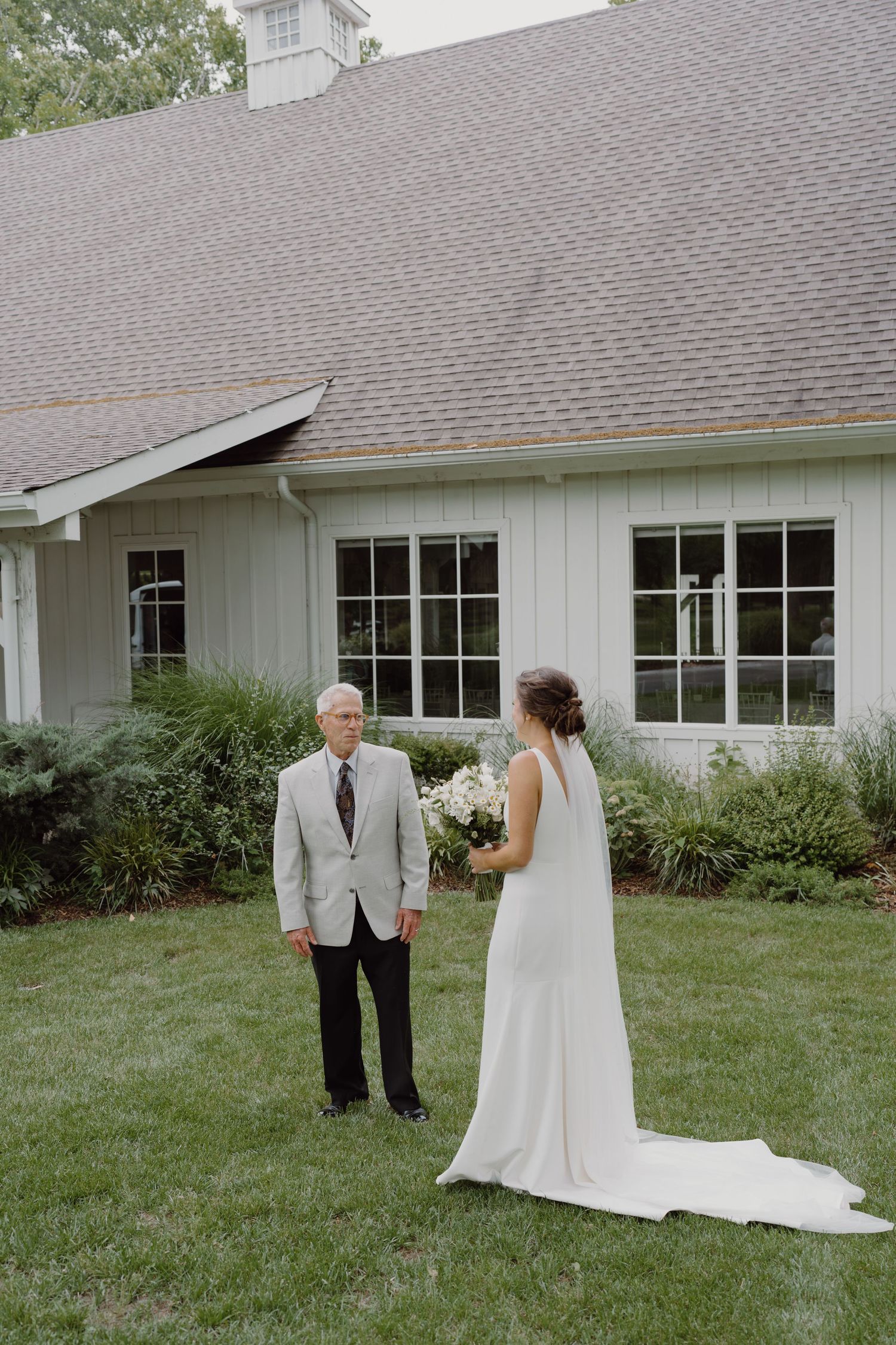A wedding first look sequence captured outside a white building with gray roof.