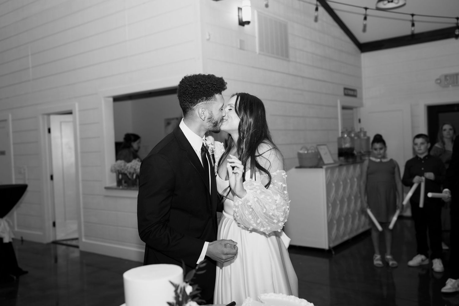 Wedding guests dance and celebrate on a white-walled reception dance floor.