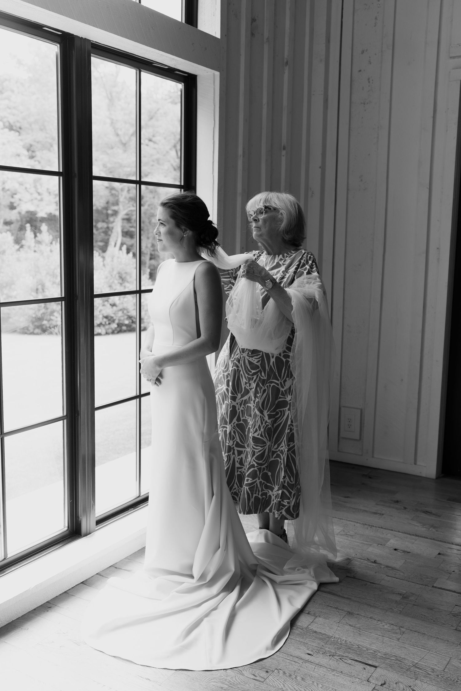 Black and white sequence of a bride in a sleek white dress by large windows.