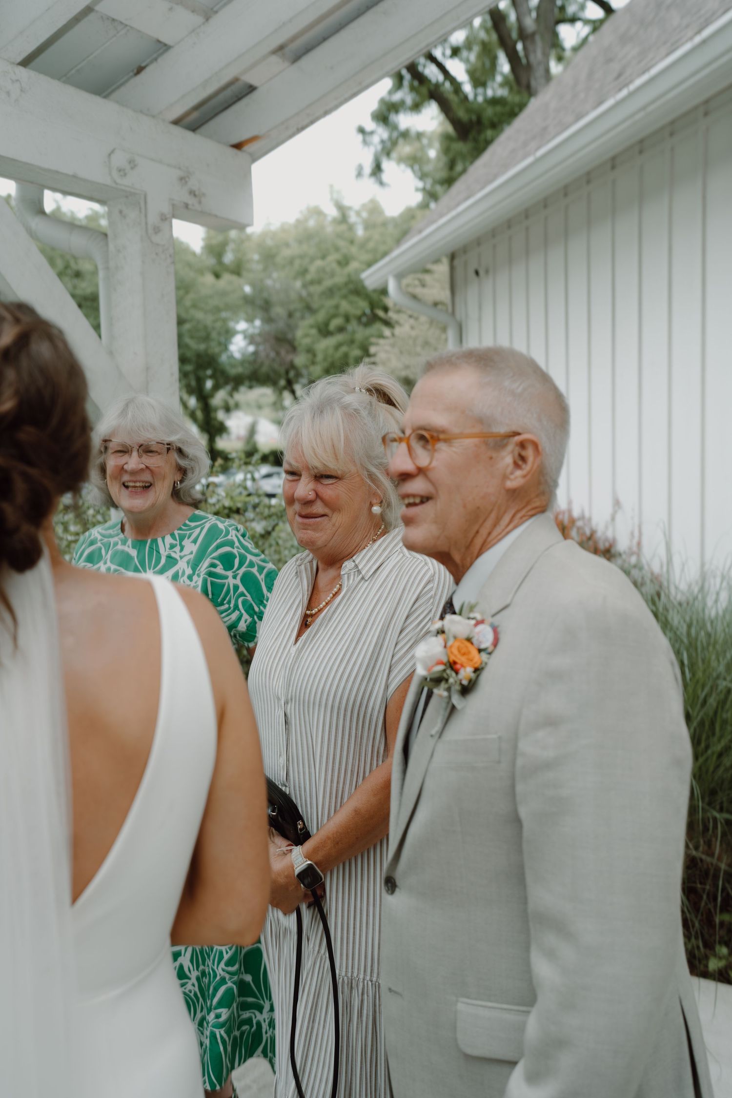 Wedding guests sharing a joyful moment on a white porch during a celebration.