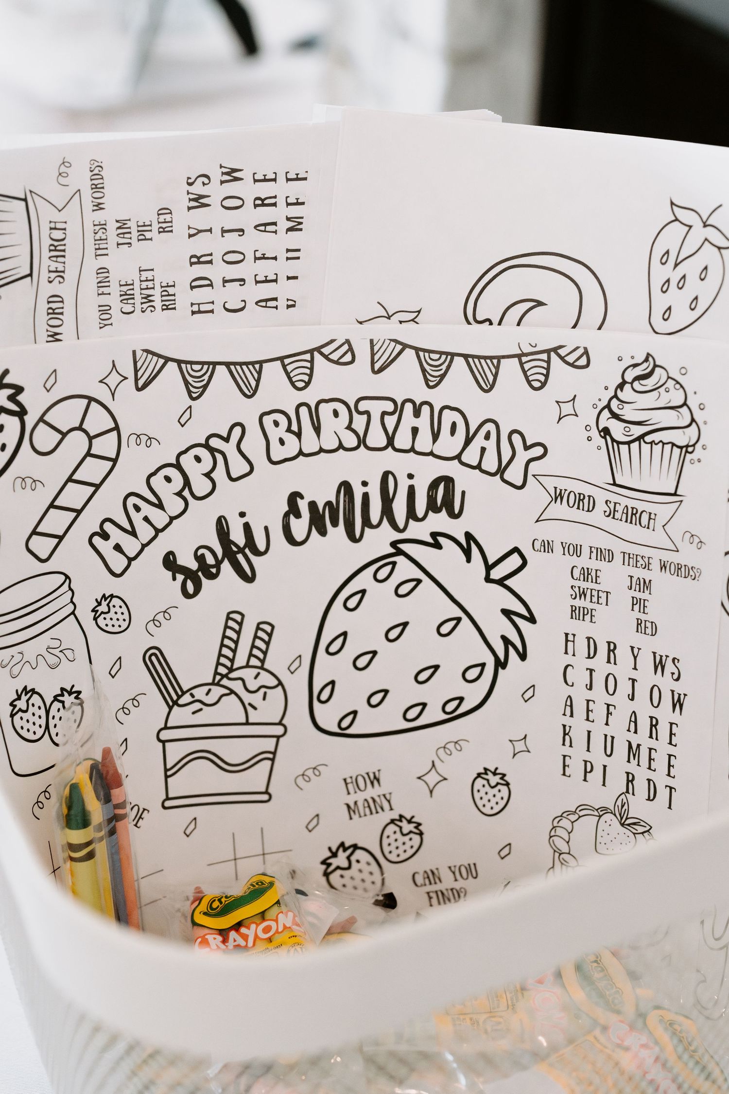 Hand-drawn birthday doodles featuring strawberries, cupcakes, and party elements on white paper.