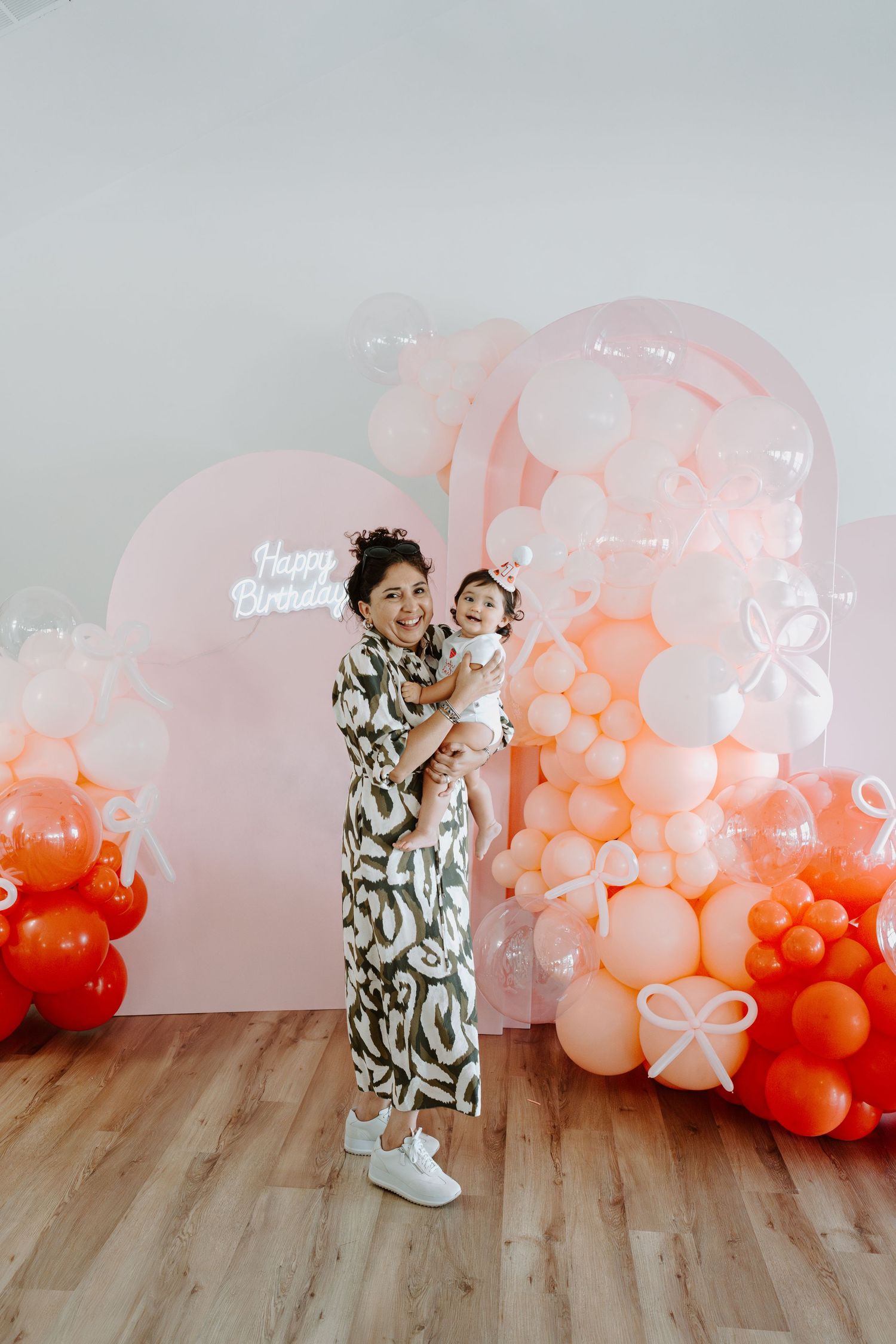 Birthday celebration scene with decorative balloon arch in shades of coral and pink.