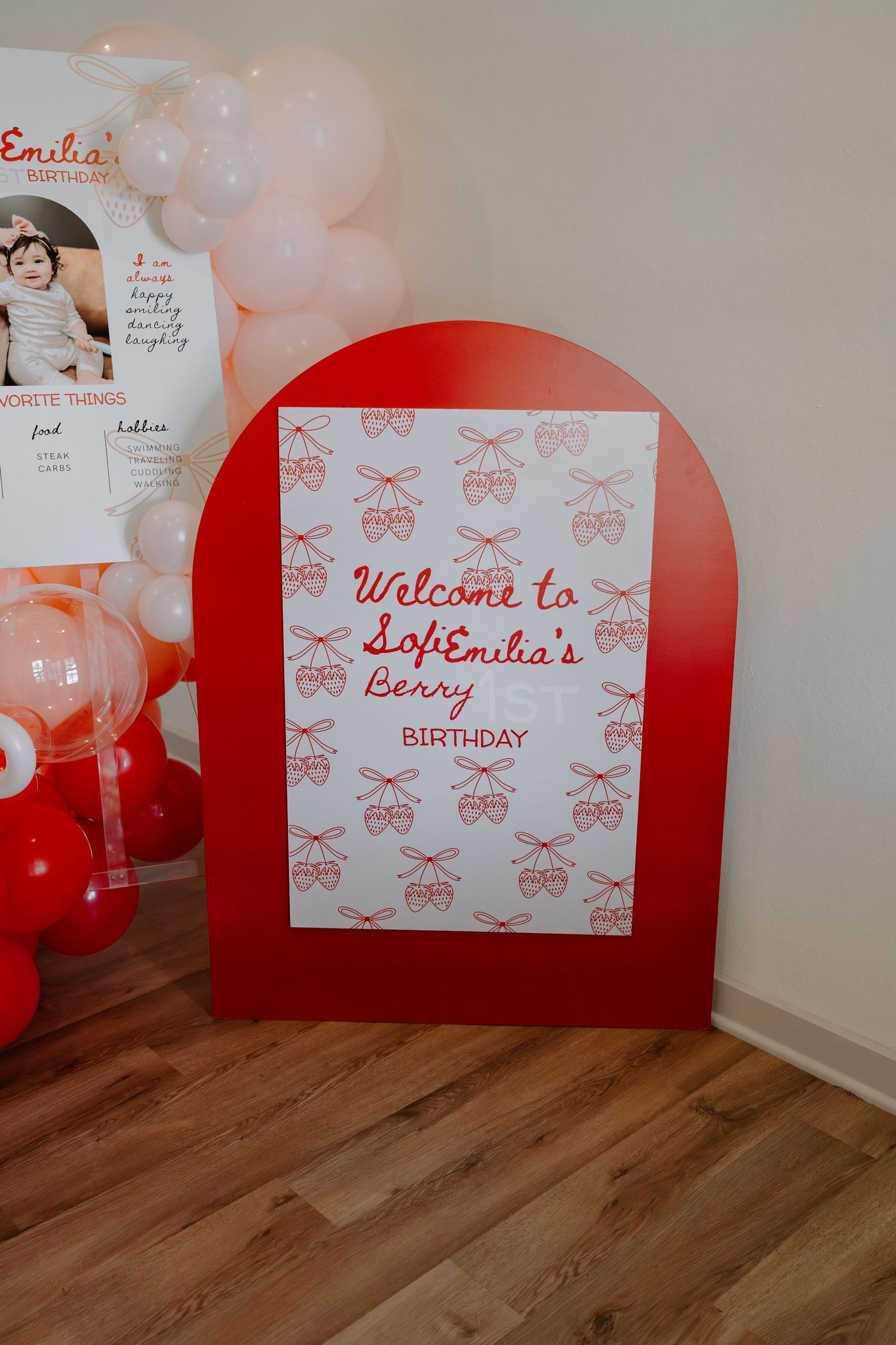 Red and white birthday party setup with decorative signs and balloon arrangements.