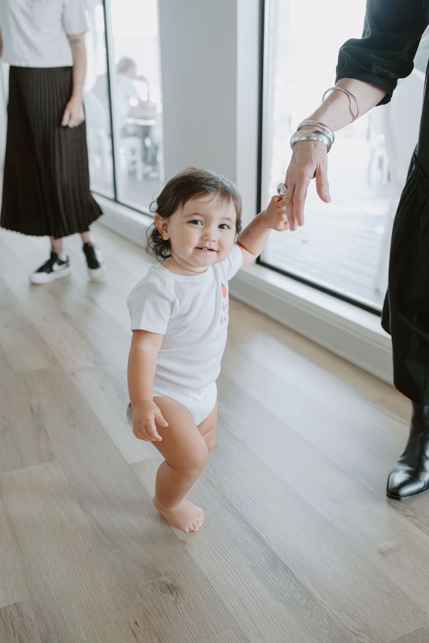 Small child walking on light wooden flooring in a bright modern space.