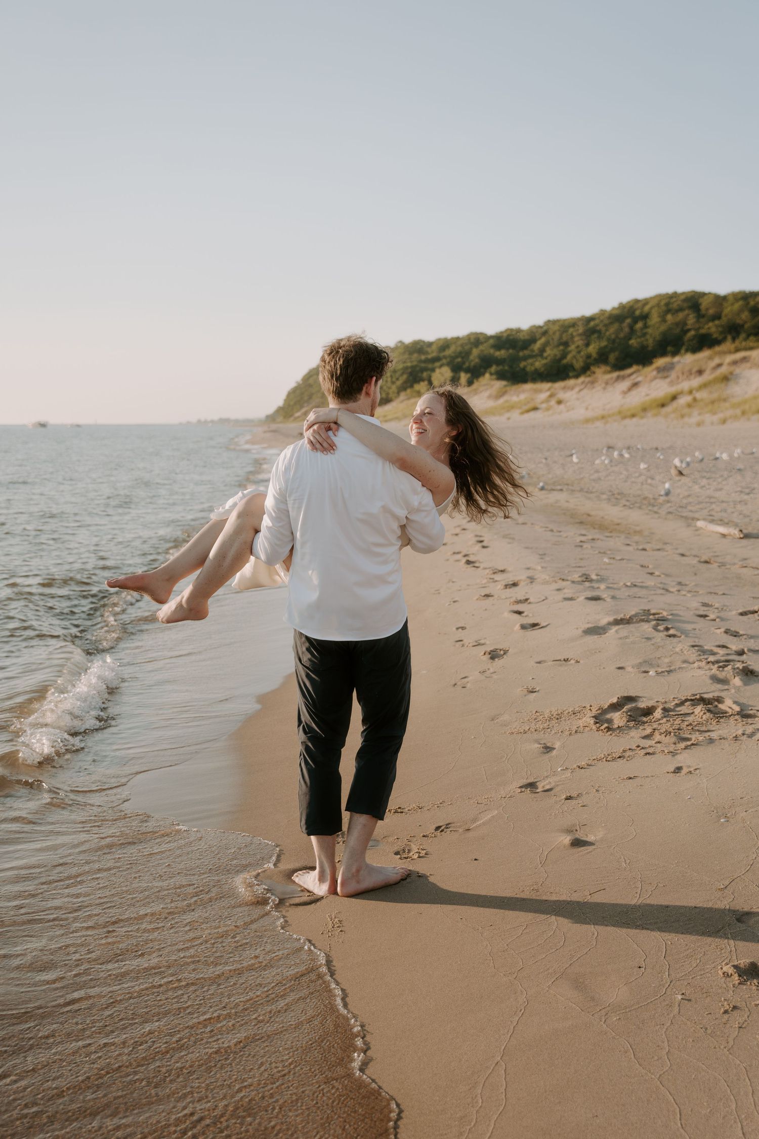 Couple enjoying a romantic walk along a scenic beach shoreline at sunset.