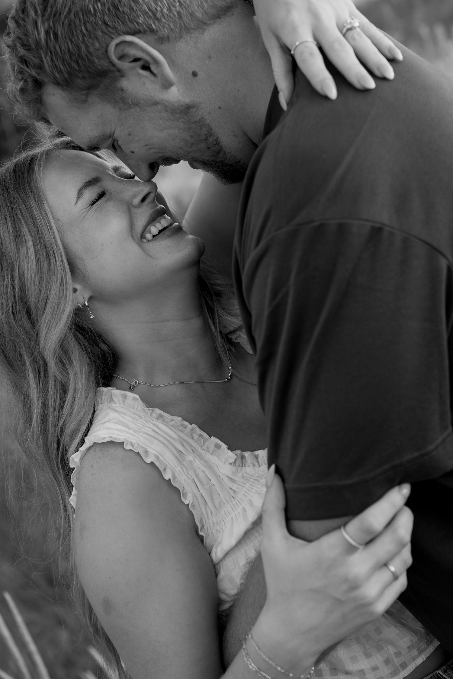 Black and white portrait of couple sharing intimate moment during beach photoshoot.