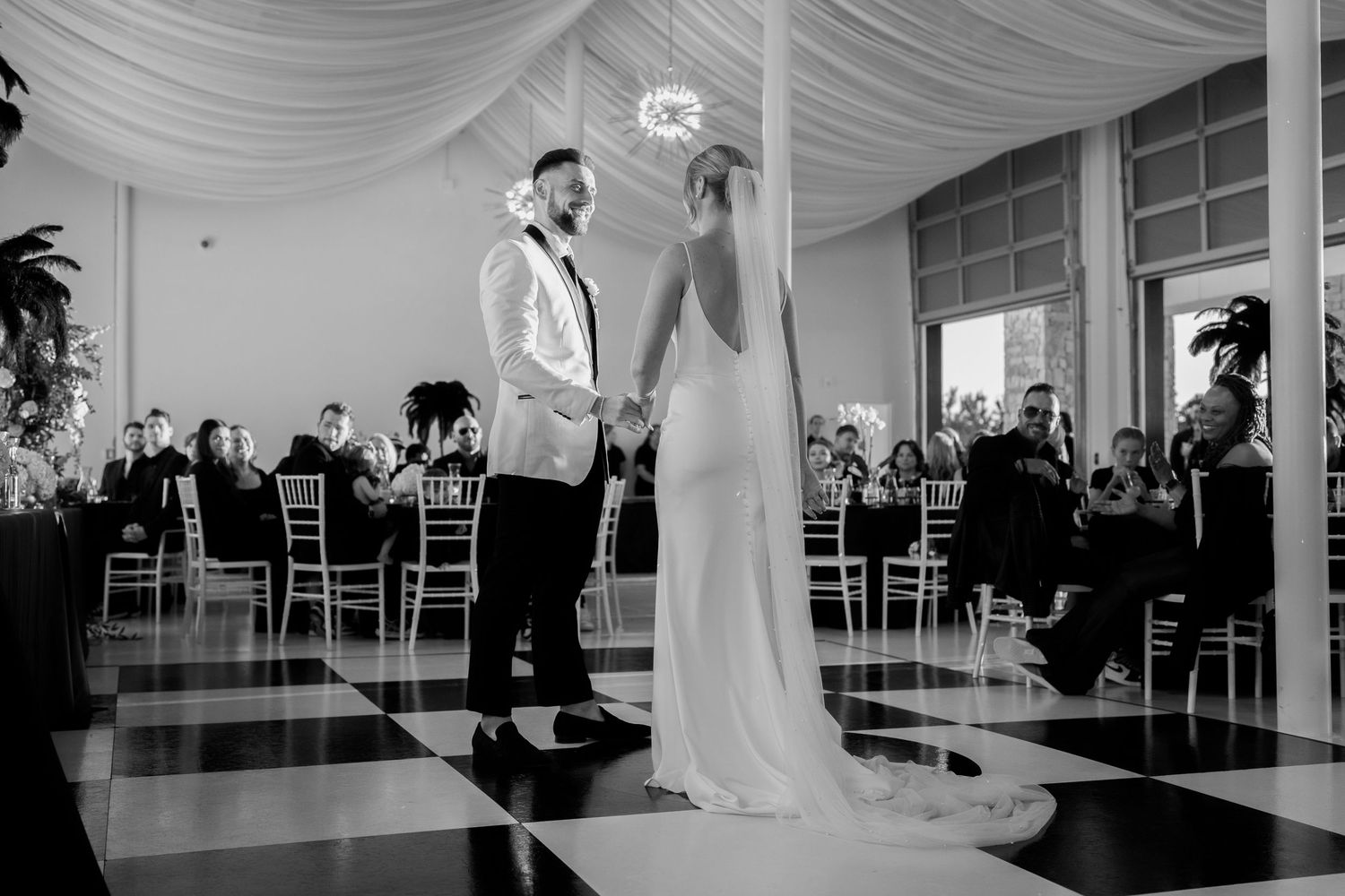 Elegant wedding ceremony space with white draping and guests seated in rows.