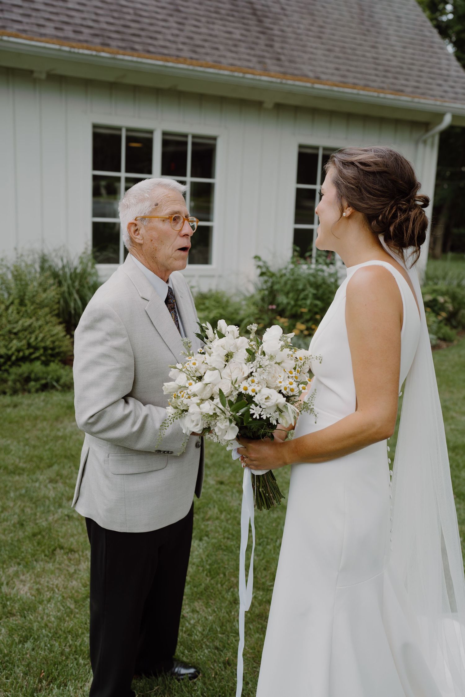 Wedding first look scene with elegant white flowers and gray suit outdoors.