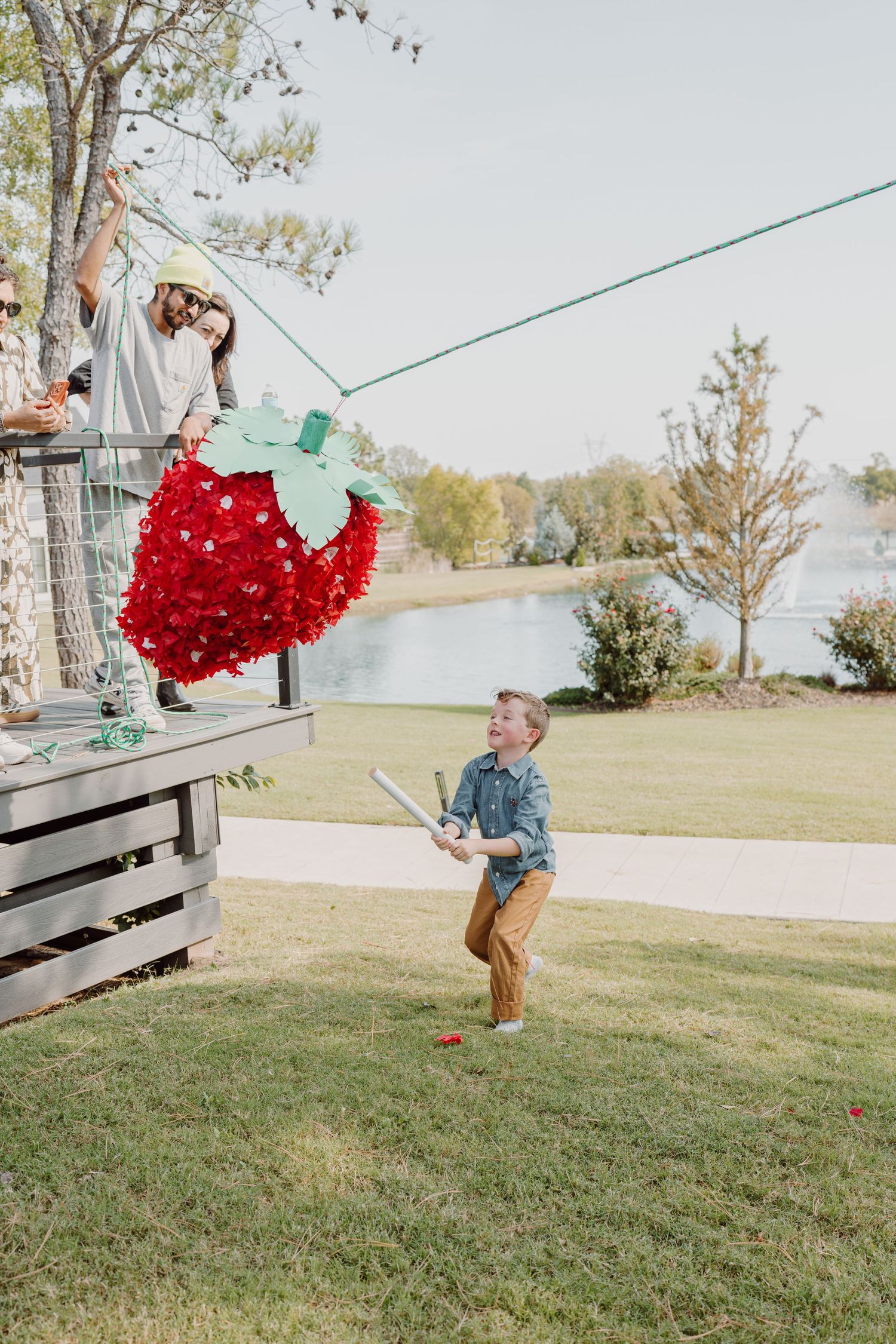 A large red heart-shaped object swings between people on a grassy hill.