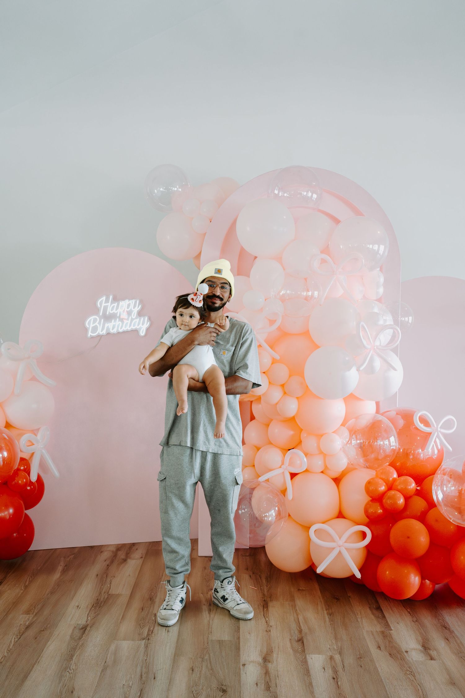 Playful birthday photoshoot setup with pink and orange balloon decorations.