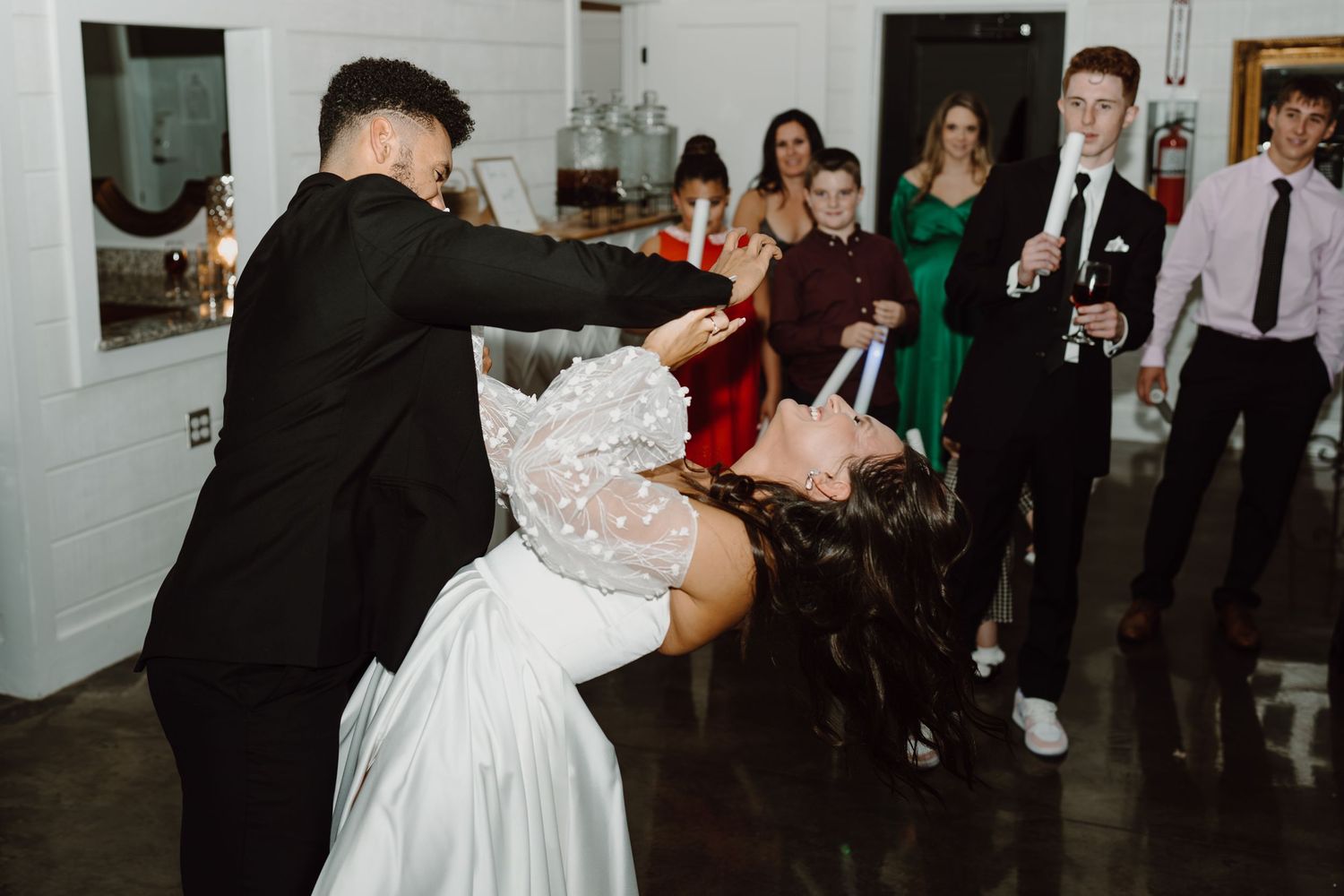 Couples dancing together at an elegant indoor wedding reception with white walls.