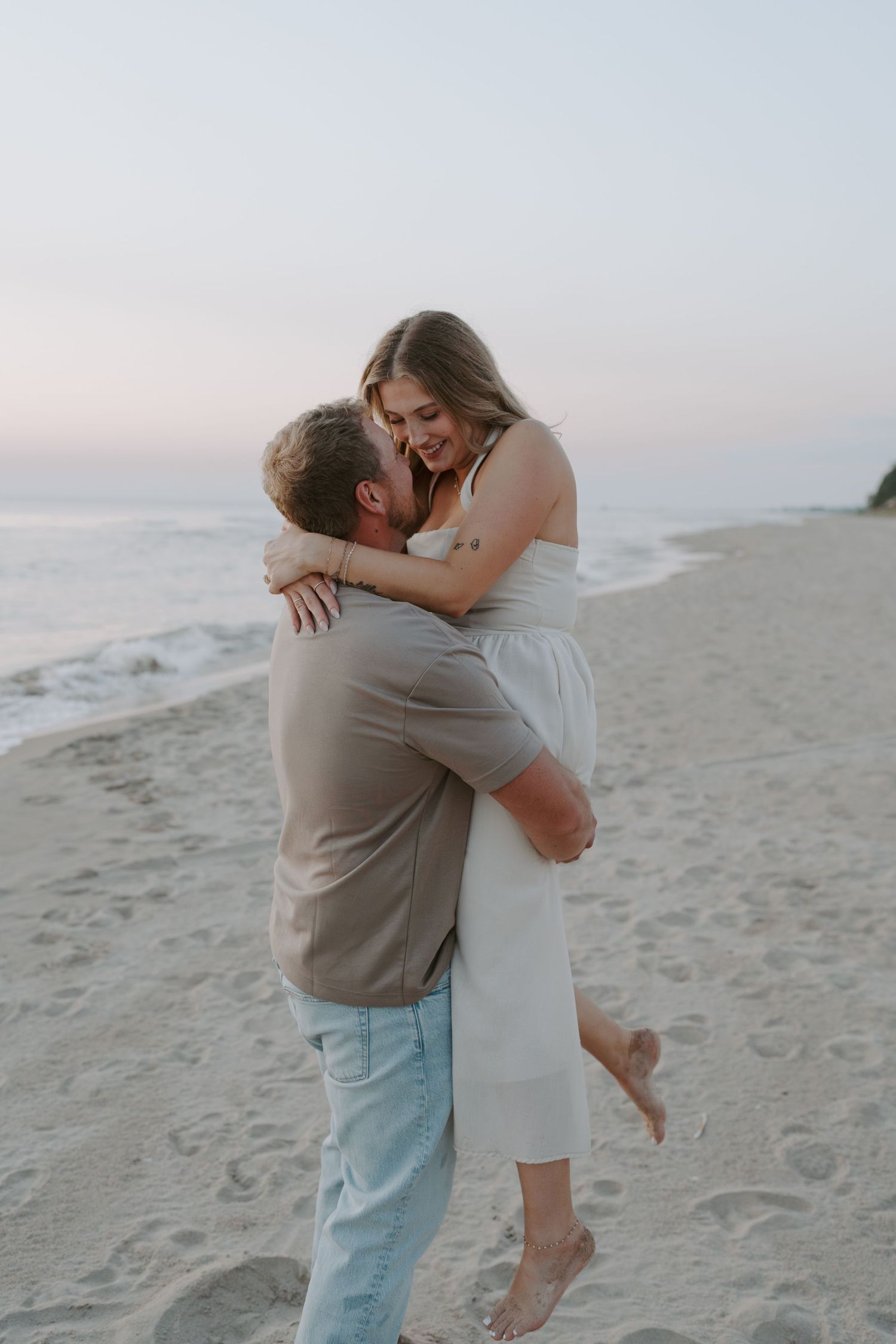 Couple sharing intimate moments and playful spins on the beach during golden hour.