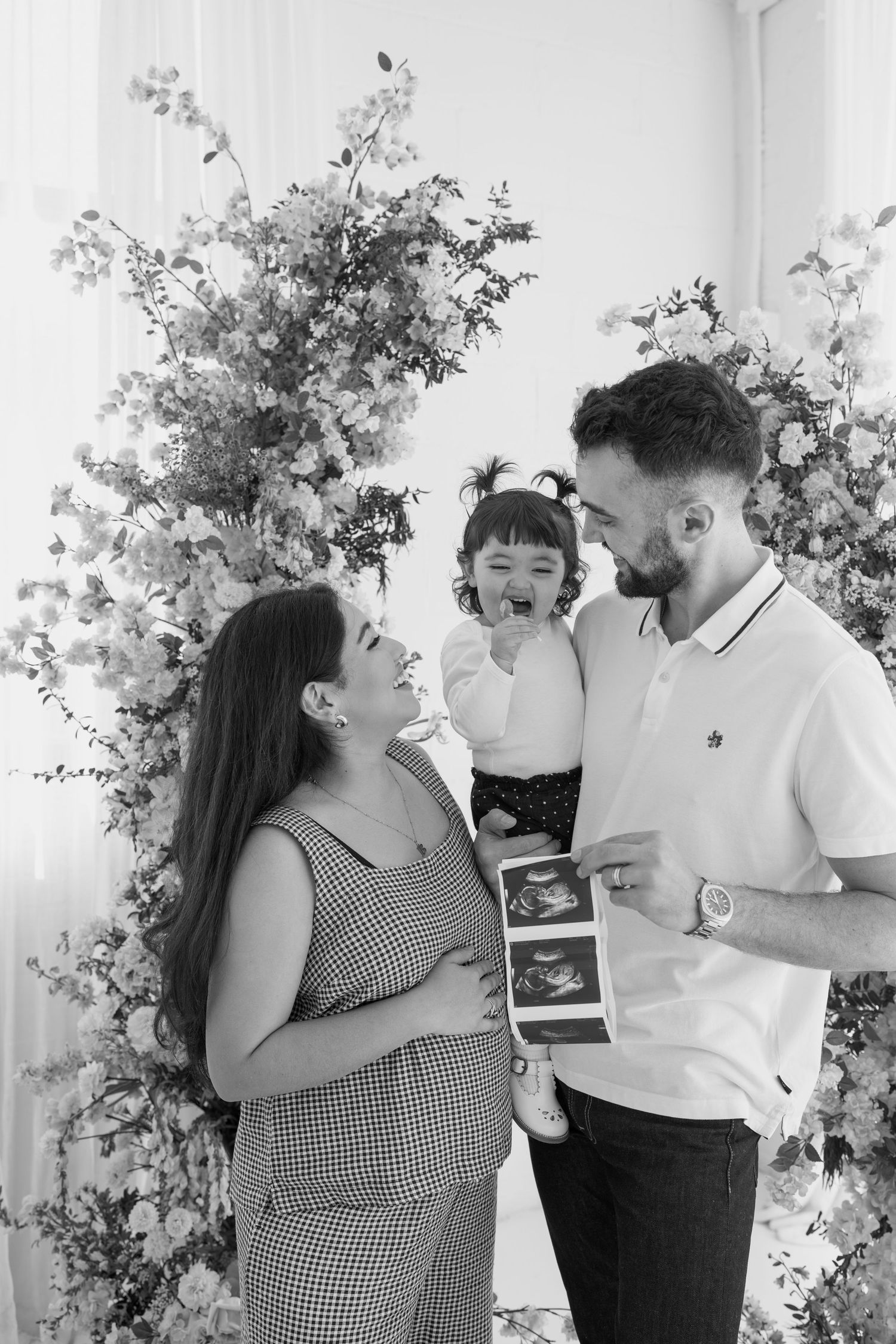 Black and white capture of a family's joyful pregnancy announcement moment.