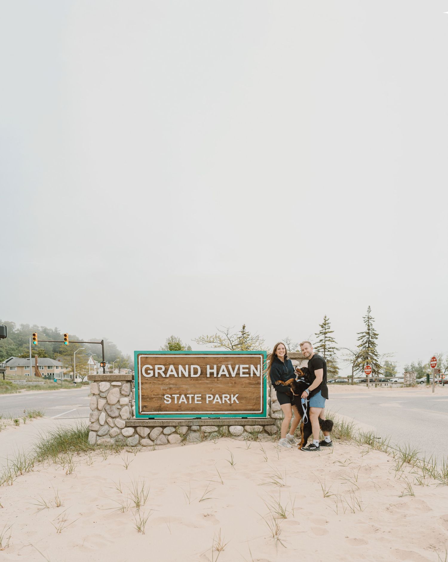 Grand Haven State Park entrance sign on a sandy beach with Lake Michigan in the background.