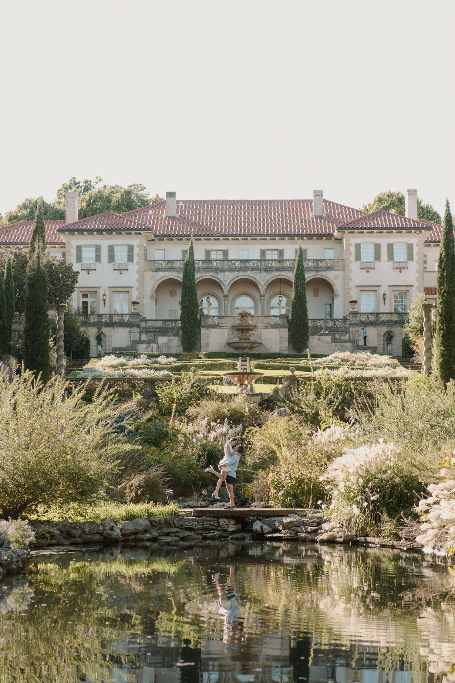 Stone archway and pond in a serene garden setting with reflective water and natural landscaping.