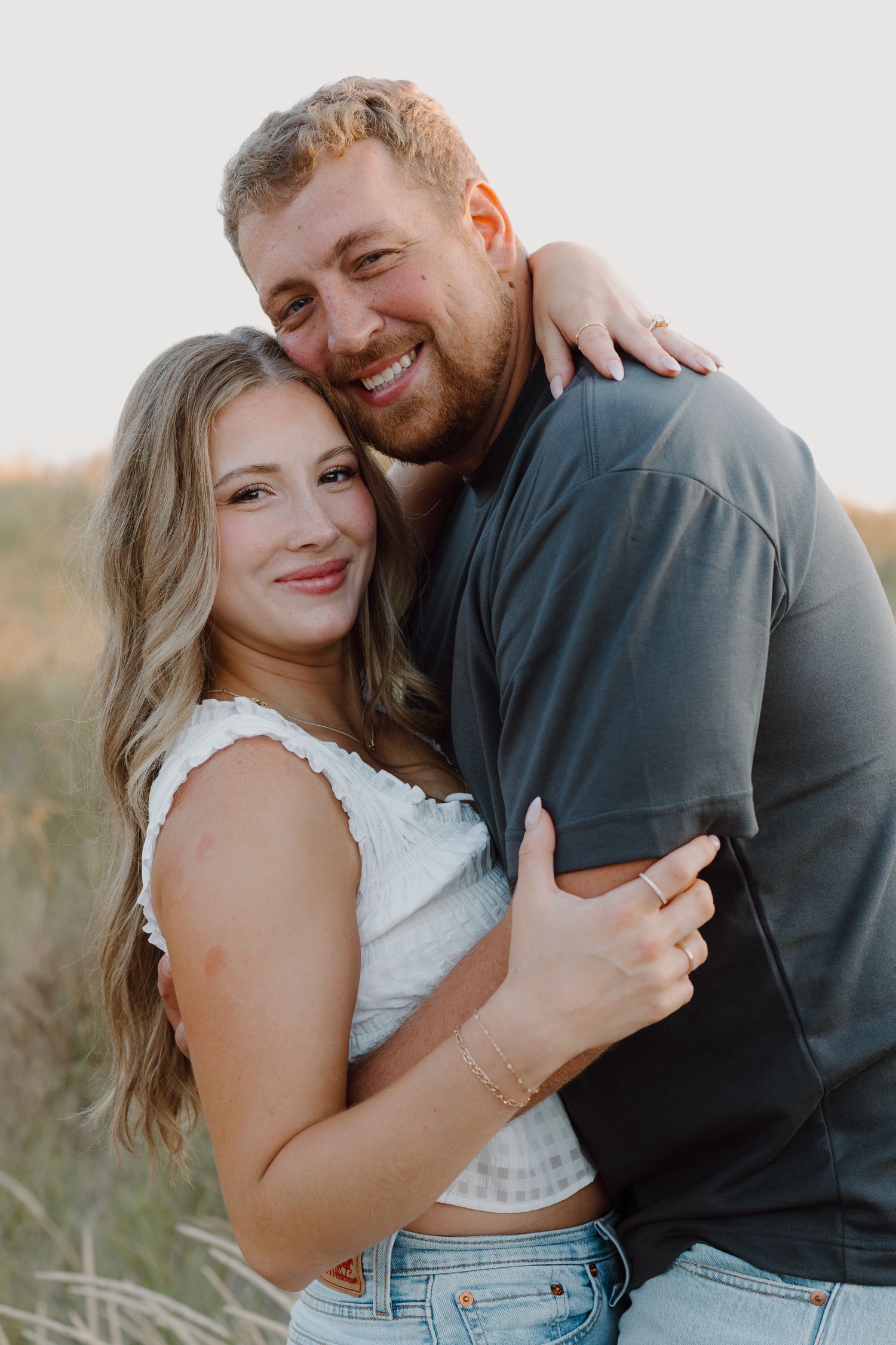 Happy couple sharing joyful moments together during outdoor photoshoot on sandy dunes.