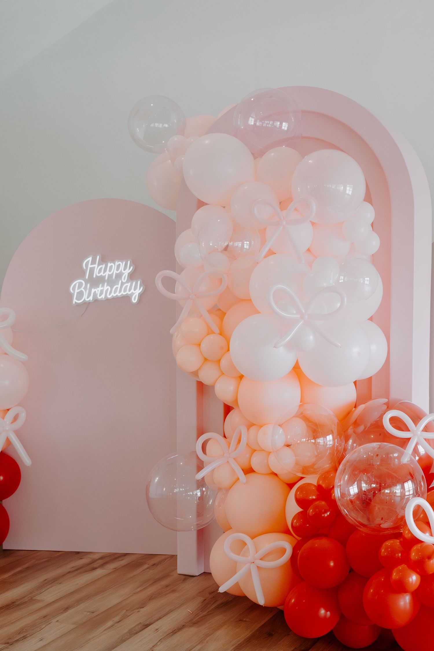 Elegant balloon arch installation in white and peach colors with Happy Birthday sign.