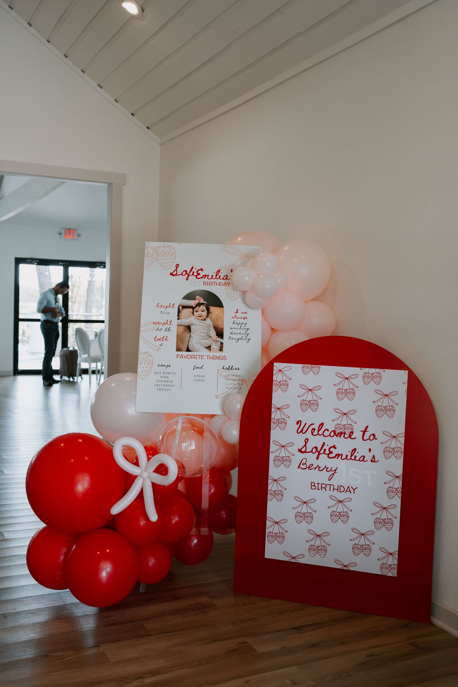 Modern white event space with red balloon decorations and welcome signage.