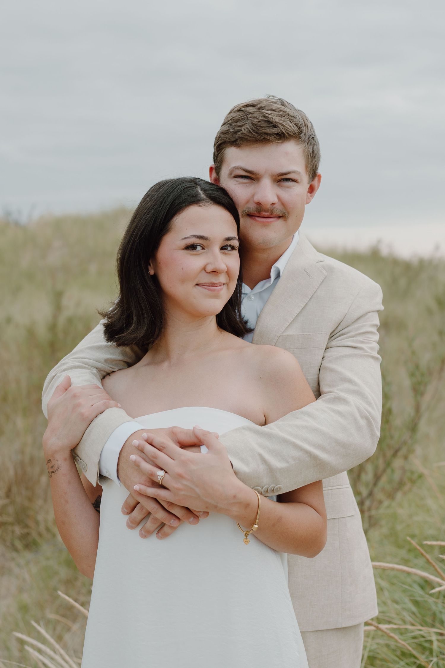 Candid wedding photography capturing playful moments between couple on sandy beach landscape.